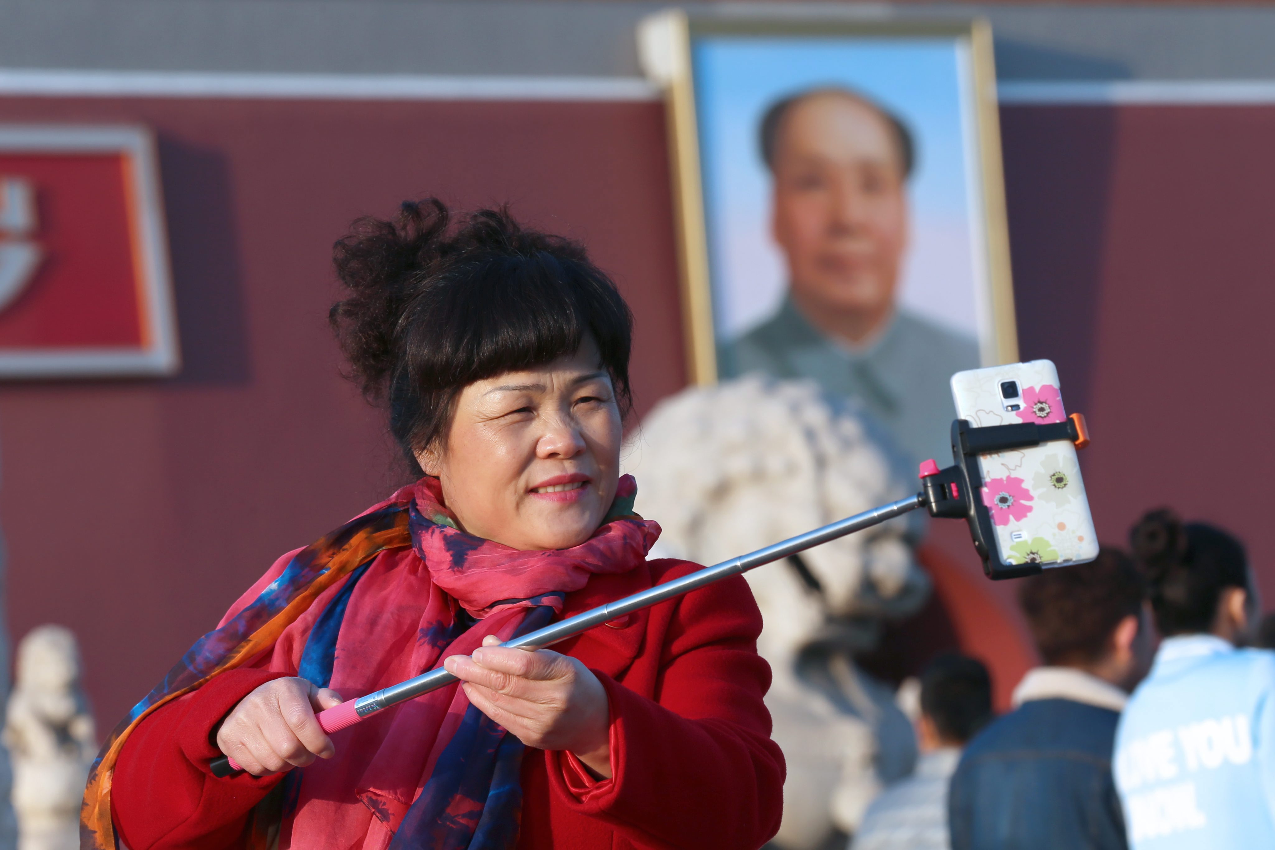 A Chinese woman uses a selfie stick to snap a picture of herself near the portrait of Mao Zedong in Beijing's Tiananmen Square. Photo: EPA