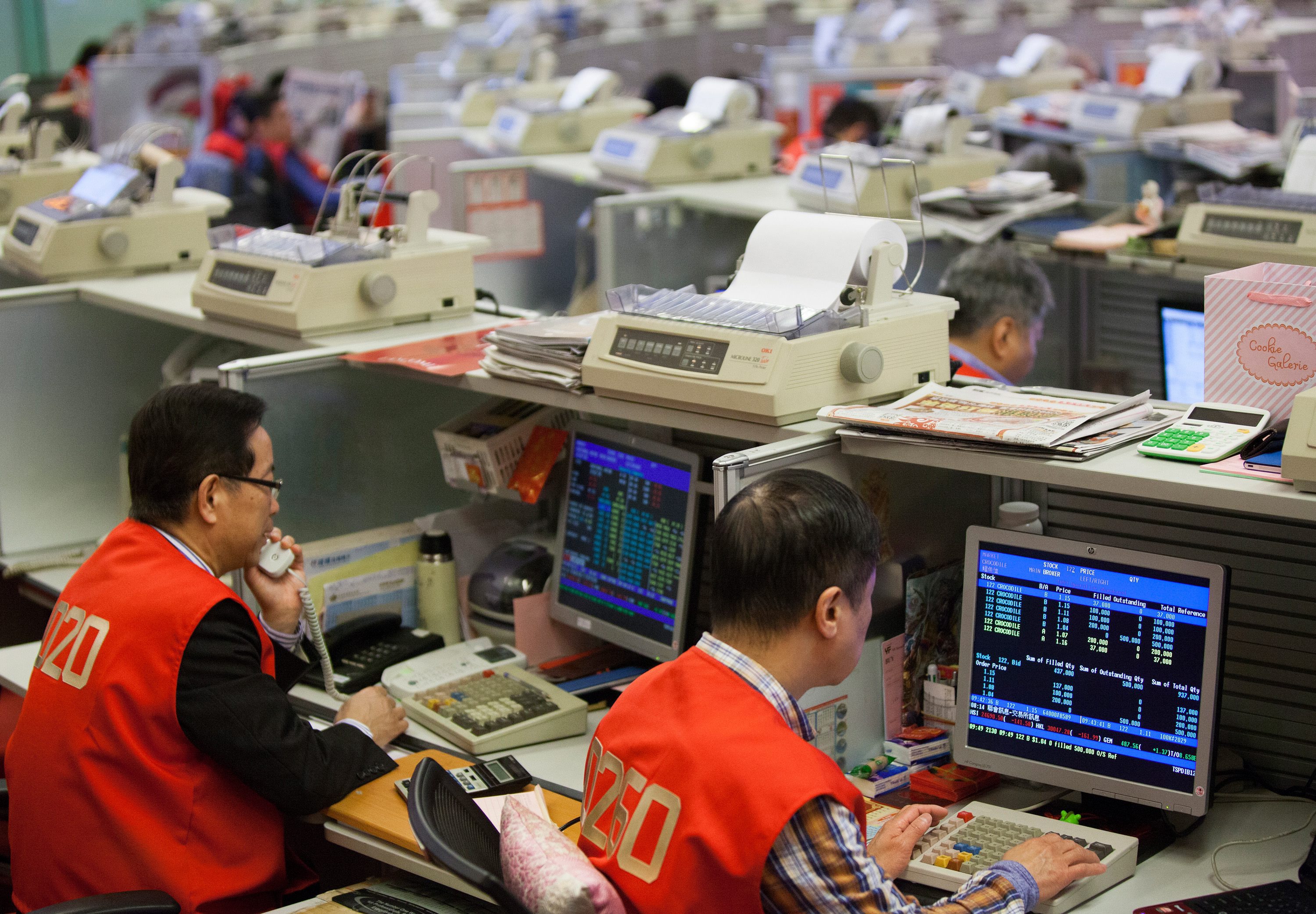 Brokers in the Hong Kong Stock Exchange keep an eye on their trading screens while filing orders. Photo: EPA