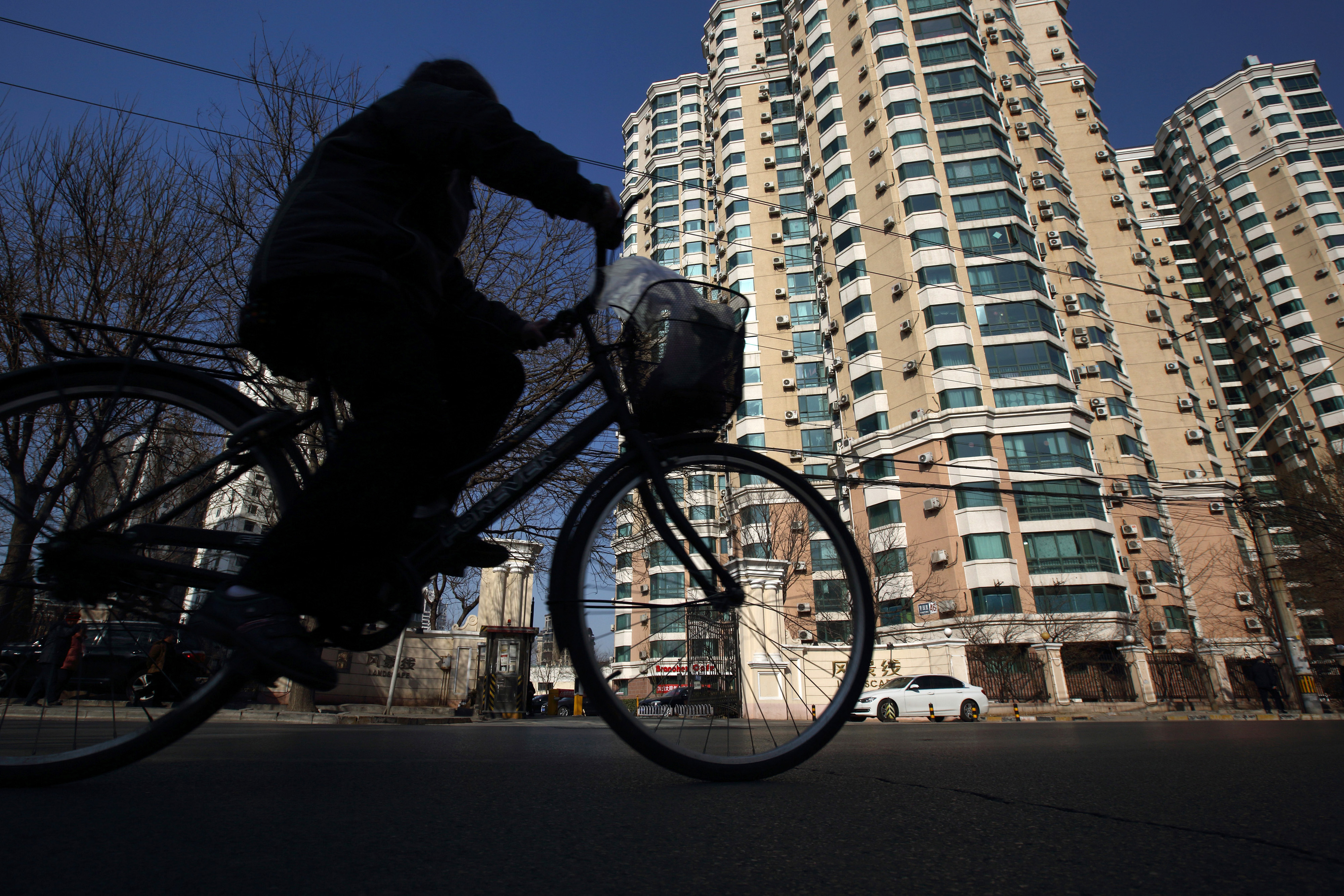 A man cycles past residential homes in Beijing. Real estate prices in 66 major cities fell in February. Photo: Bloomberg