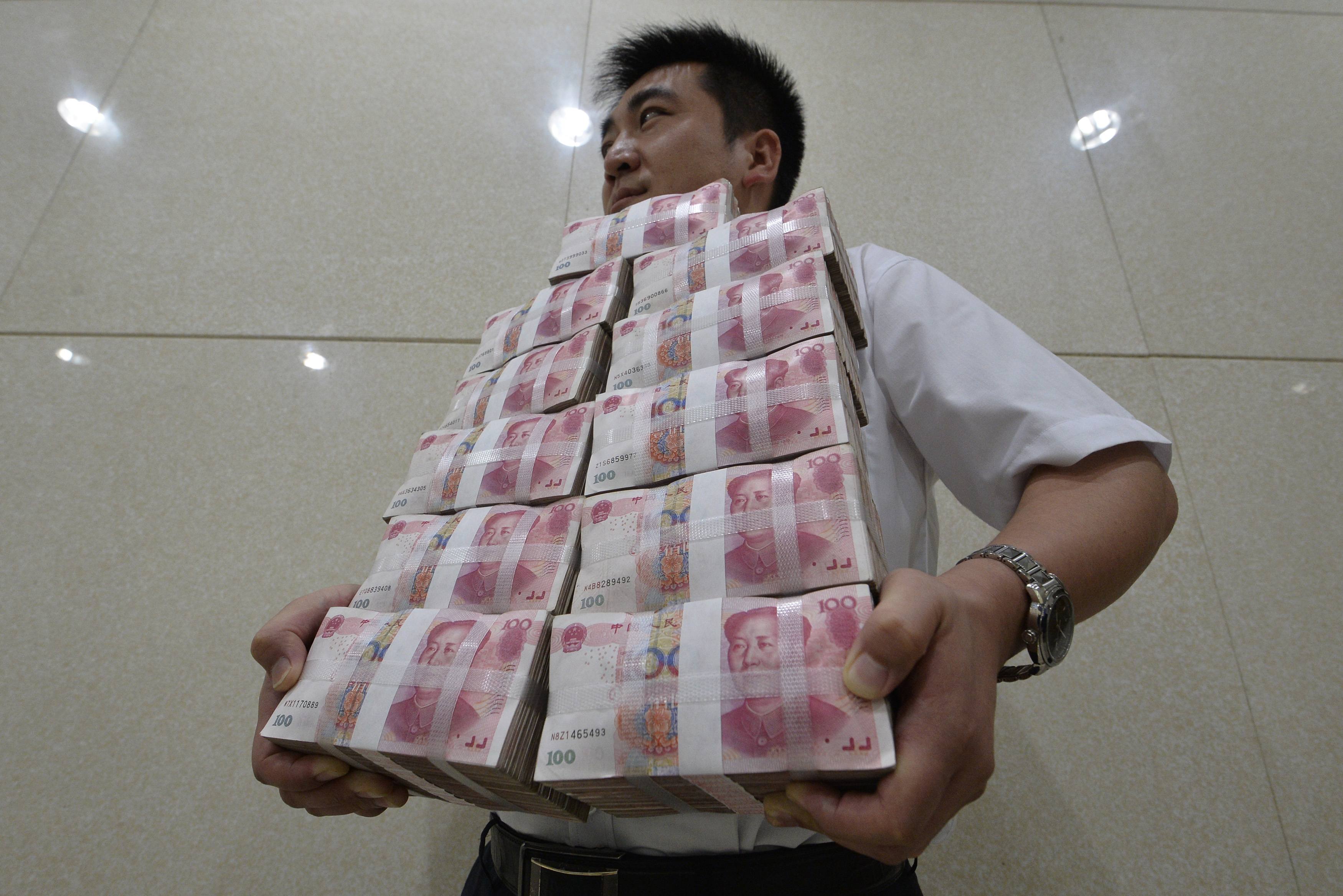 A man balances chin-high bundles of yuan in China as the currency's offshore spot market gained the most in a week. Photo: Reuters
 