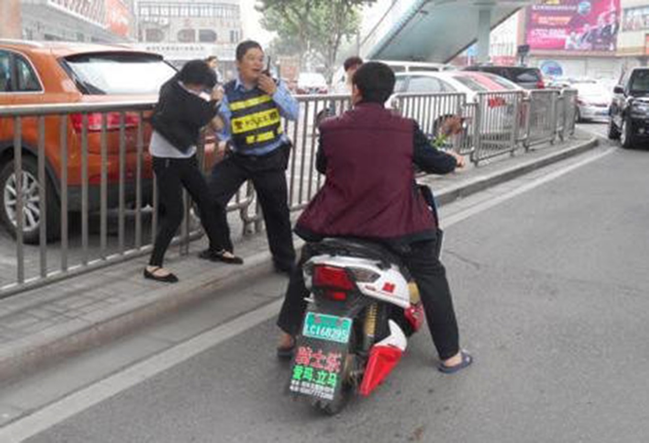 The police officer and woman passenger scuffle on a road in Shenyang. Photo: Weibo