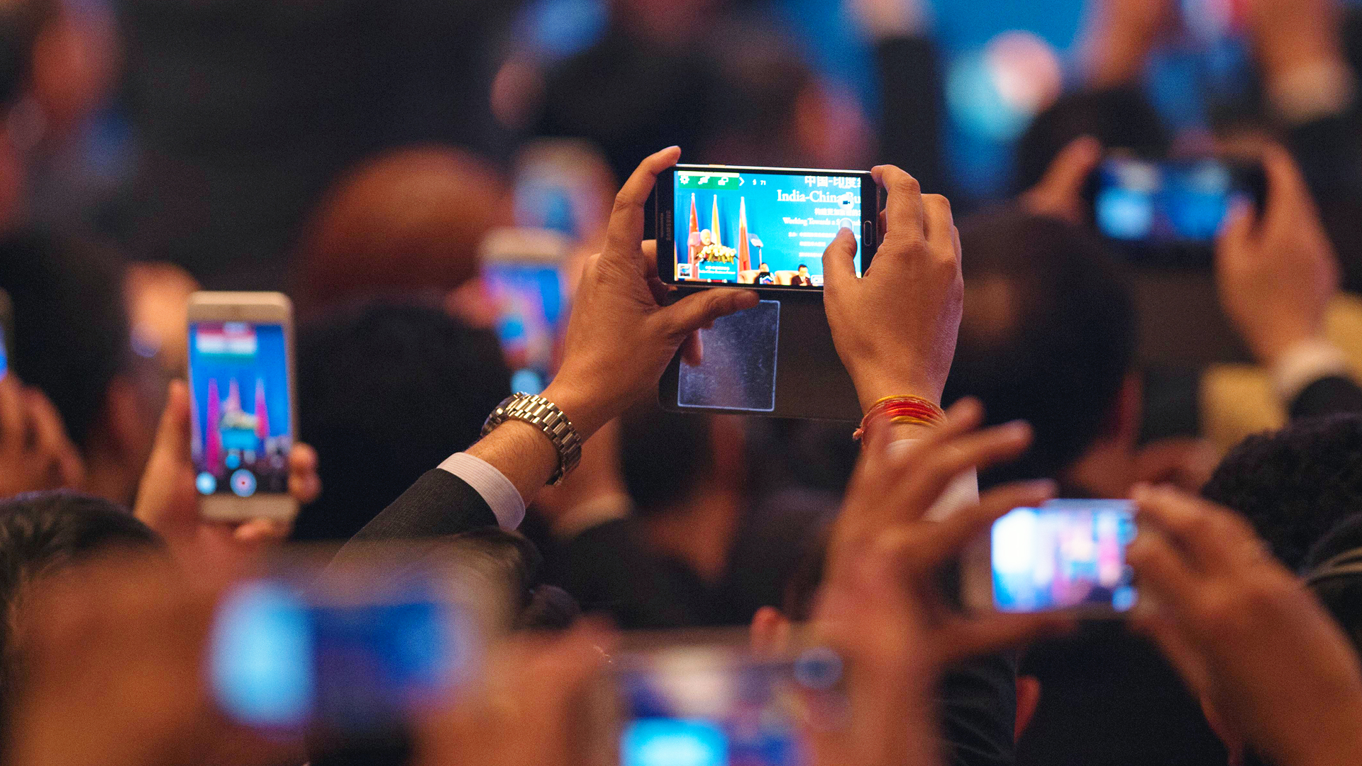 India's Prime Minister Narendra Modi is seen on mobile phone screens while he delivers a speech at the India-China Business Forum in Shanghai on May 16, 2015. Photo: AFP