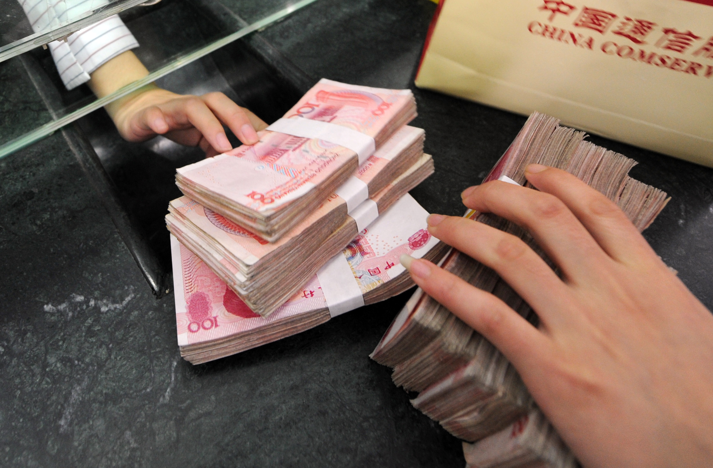Stacks of Chinese yuan change hands as the currency was virtually flat on Friday against the US dollar. Photo: AFP