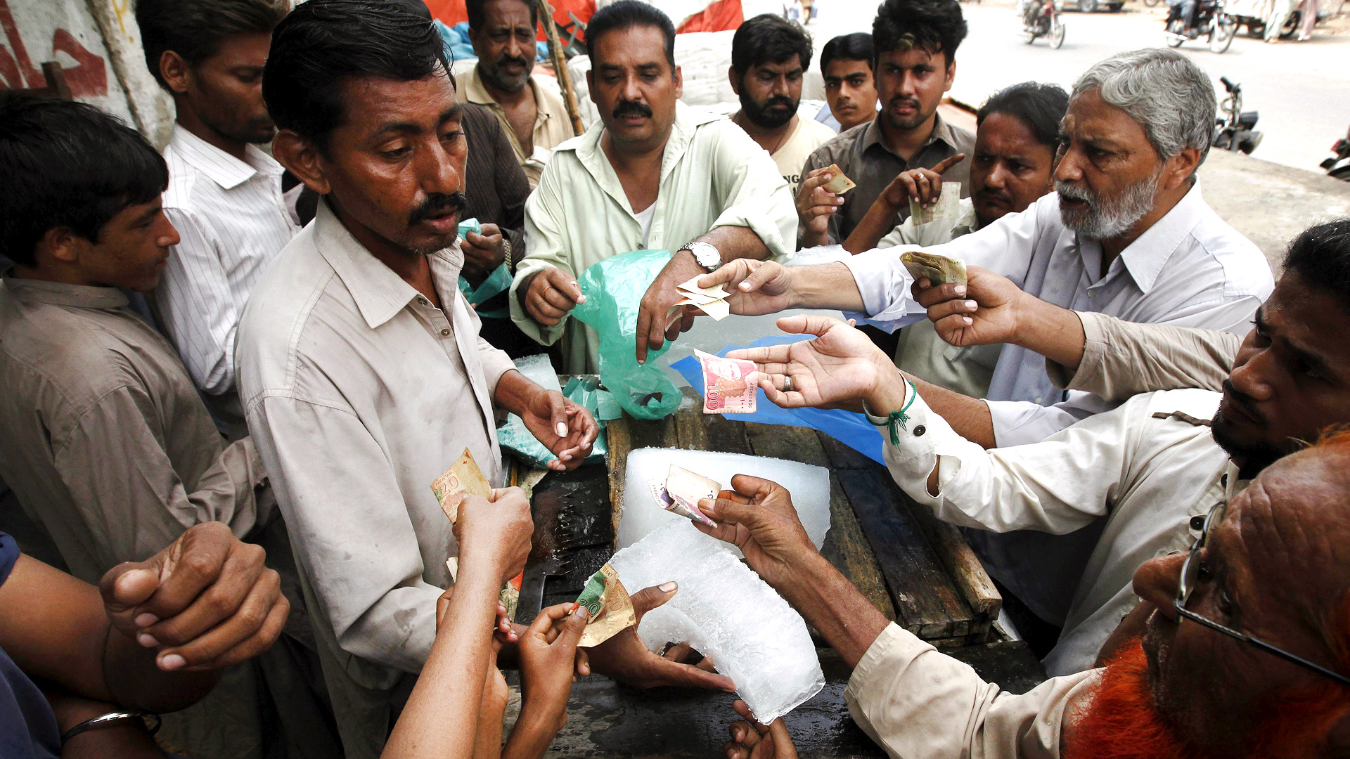 People buy ice blocks from a vendor along a road during a heat wave in Karachi, Pakistan. Pakistan's financial capital of Karachi is wilting in the four-day heat wave that has killed more than 780 people, a health charity said on Wednesday, as the government declared a holiday in the city to encourage people to stay home and cool off. Photo: Reuters
