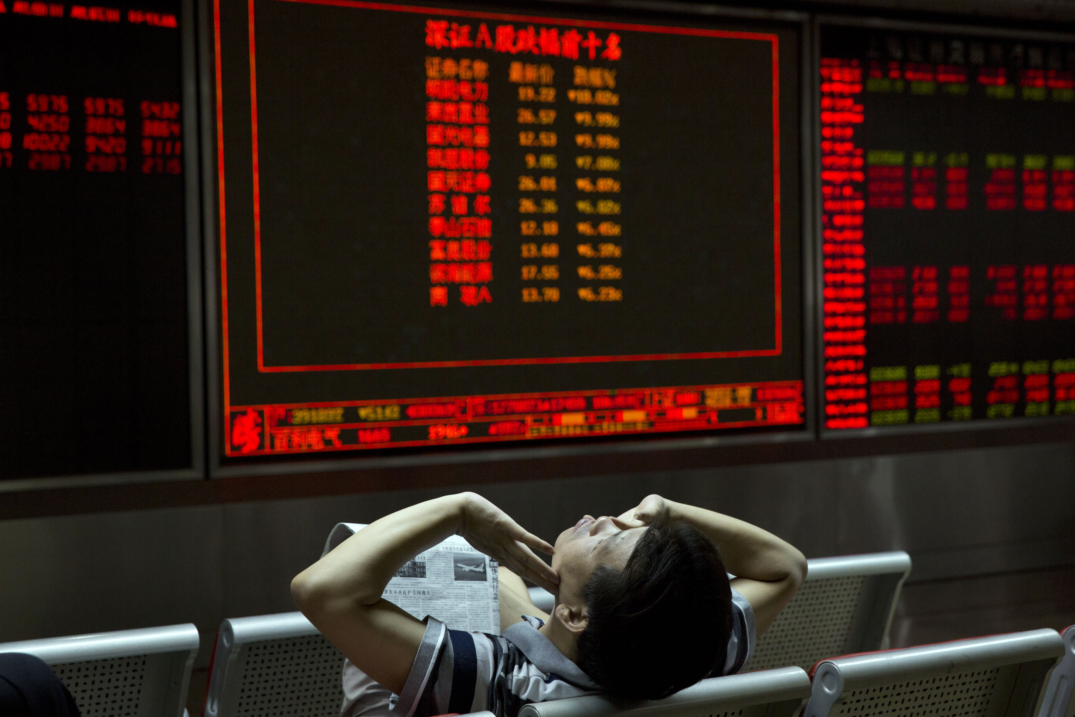 An investor in China's equity market stretches while taking a break from monitoring prices at a brokerage in Beijing. Photo: AP