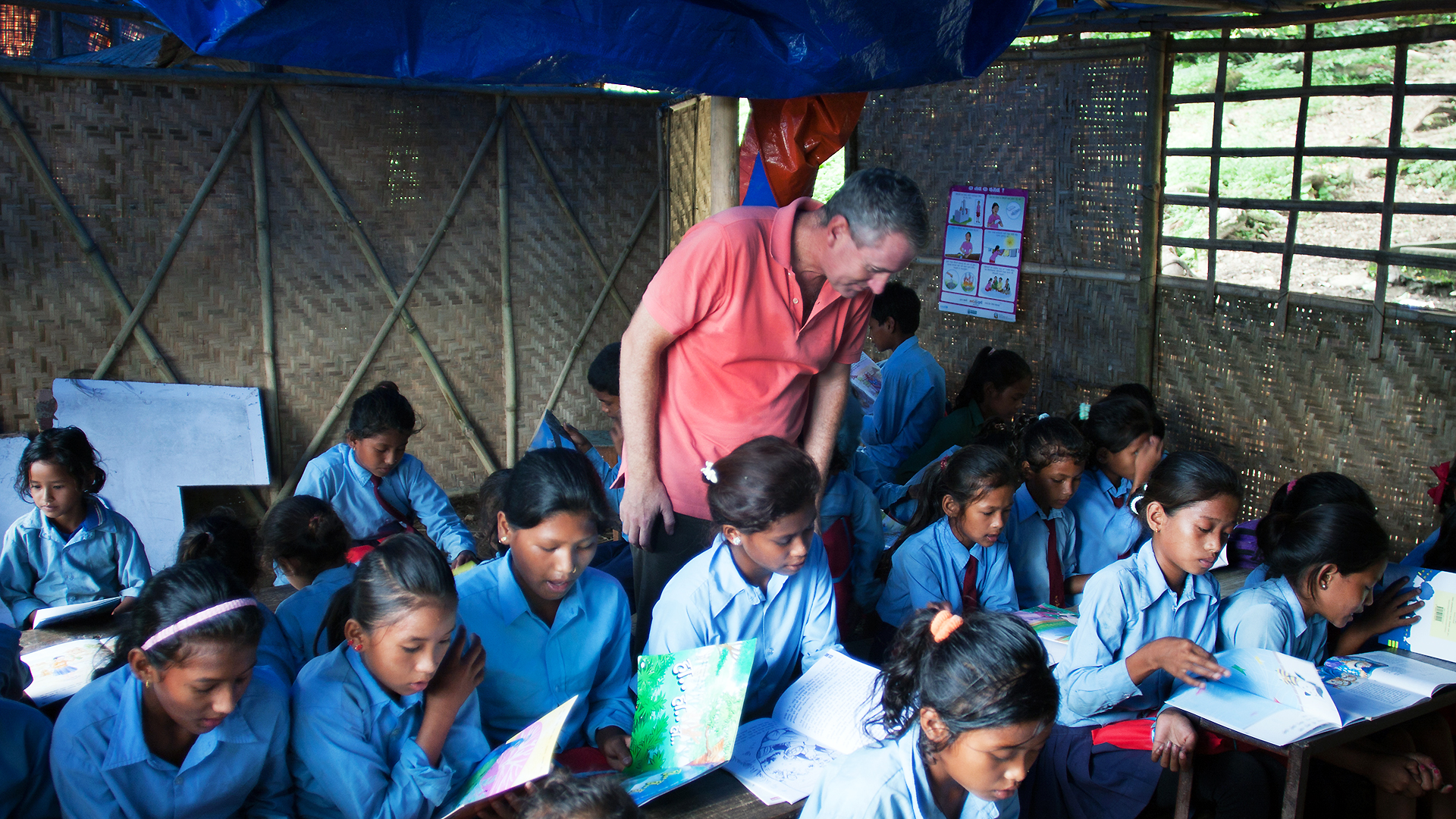 John Wood of Room to Read observes a class in the temporary learning centre in Shree Mandredhunga Primary School in Nuwakot. It is estimated that over one million  children in Nepal's earthquake-affected regions are studying in such makeshift centres. Photo: Rishi Amatya/Room to Read 
