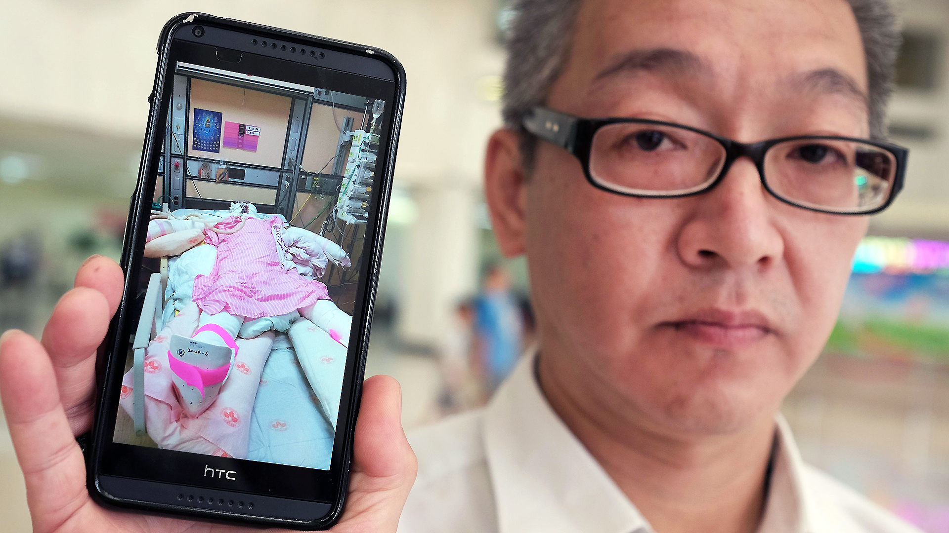 Michael Chu displays an image of his 18-year-old daughter, Julie, at a hospital in Taipei. Julie suffered burns to more than 70 per cent of her body in the water park explosion. Photo: AFP