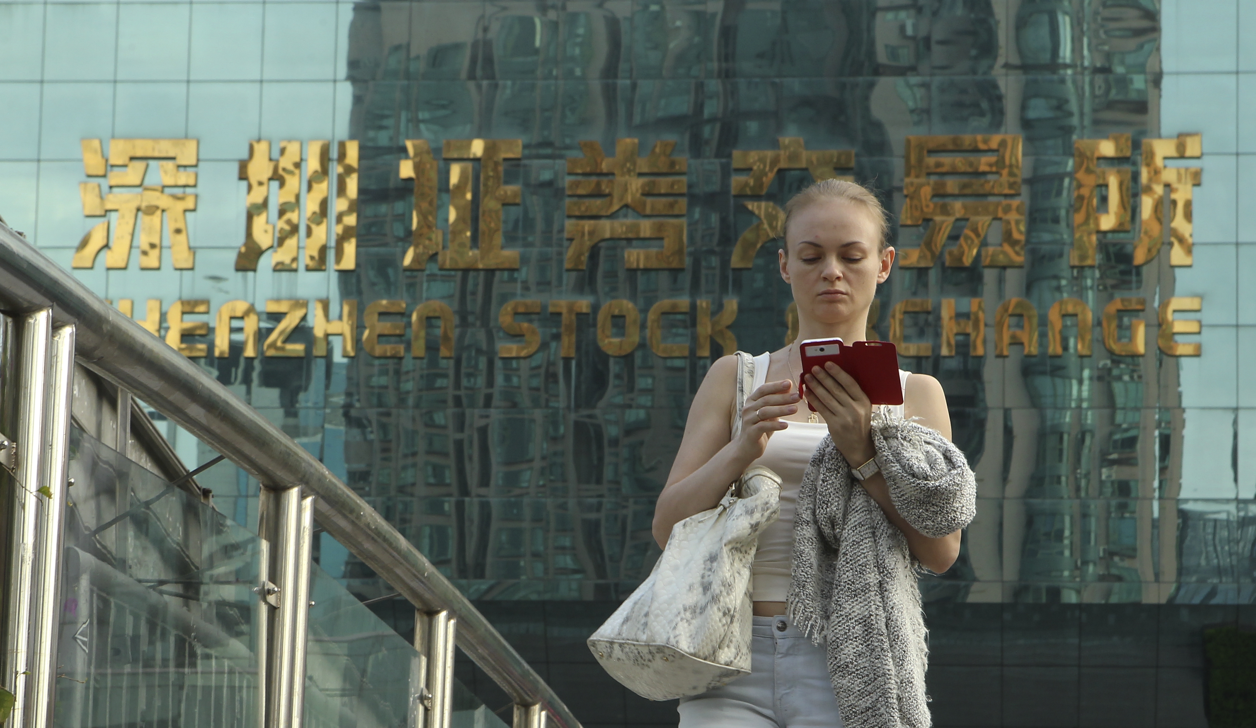 A woman walks away from the Shenzhen stock exchange as markets in mainland China and Hong Kong may continue to see downside risks in the days ahead. Photo: ImagineChina