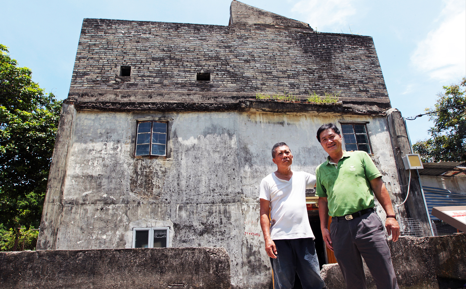 Chiu Ping-kan (left), elder brother of Chiu Ping-yin (right), poses for a photograph outside the fortified structure at No. 55 Ha Pak Nai Tsuen, Yuen Long. Photo: Bruce Yan