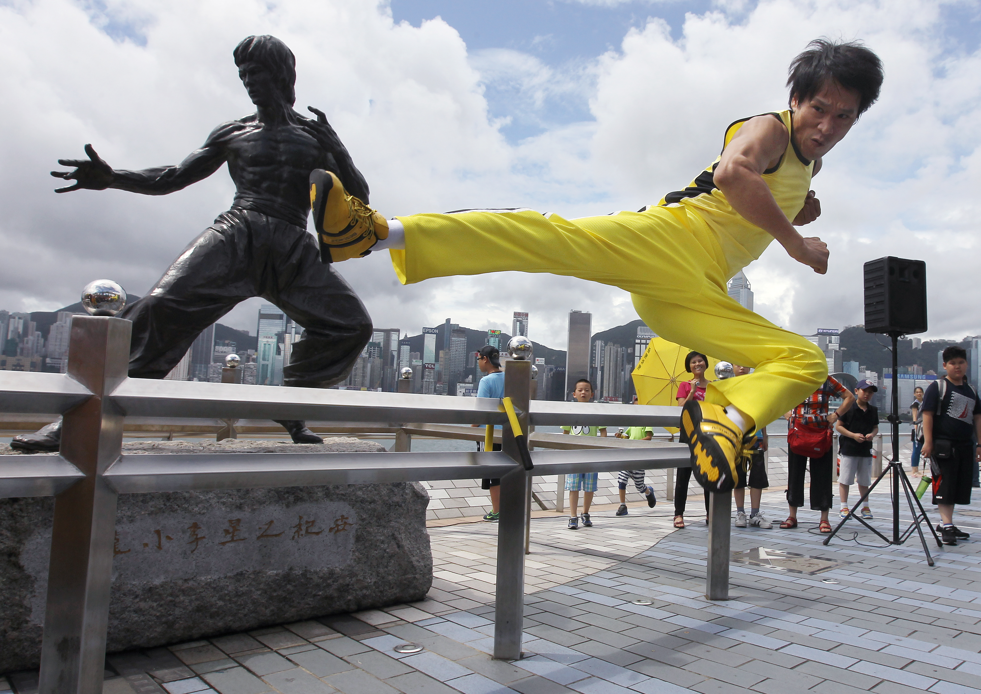 Tourists look on as a Chinese actor mirrors the fighting skills of film icon Bruce Lee at the Avenue of Stars, which offers great views of the Hong Kong skyline. Photo: Samantha SinPhoto: Edward Wong