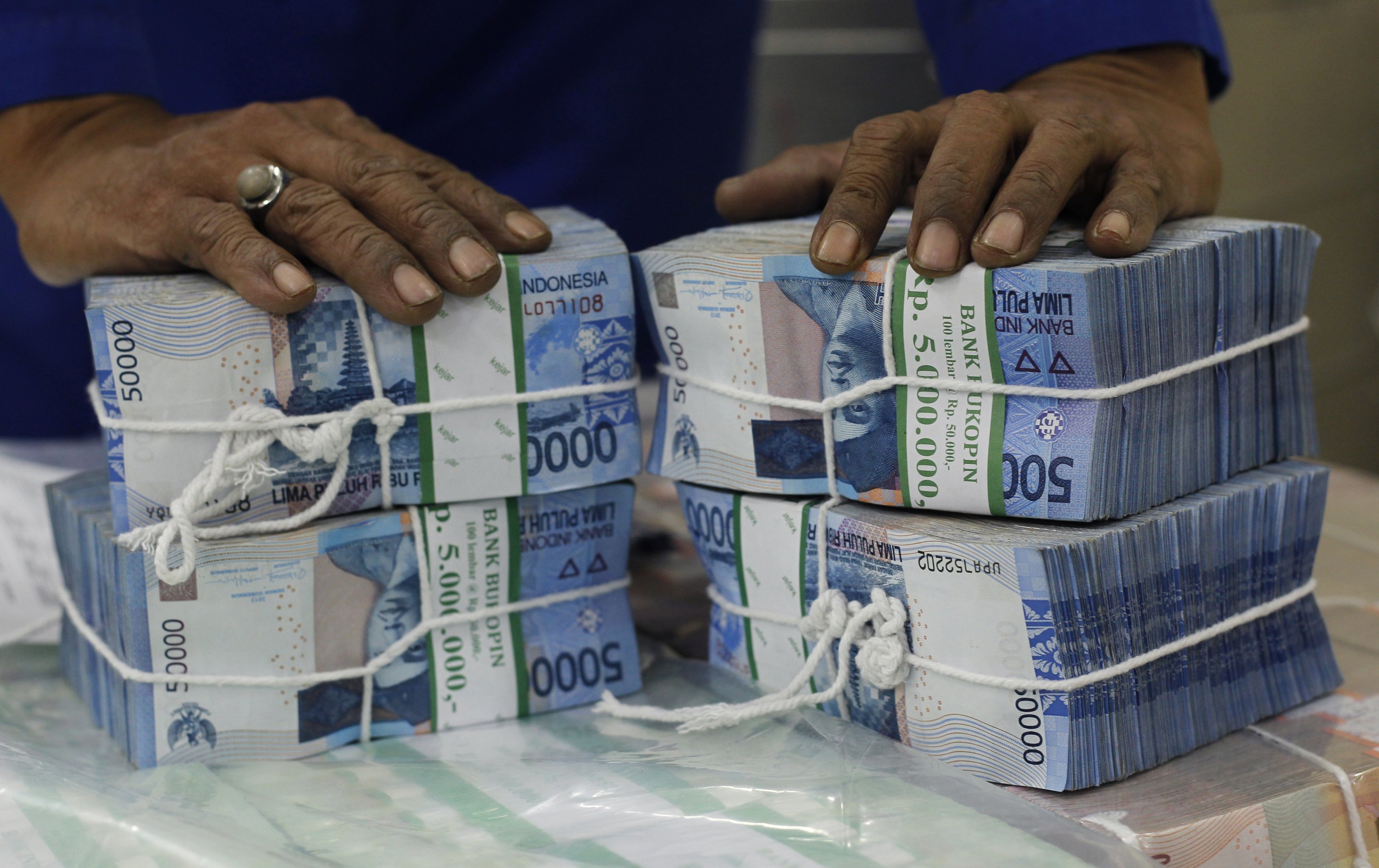 A worker prepares bundles of rupiah bank notes in Jakarta as sharp falls in emerging market currencies will also likely lead to further declines in emerging market equities. Photo: Reuters 