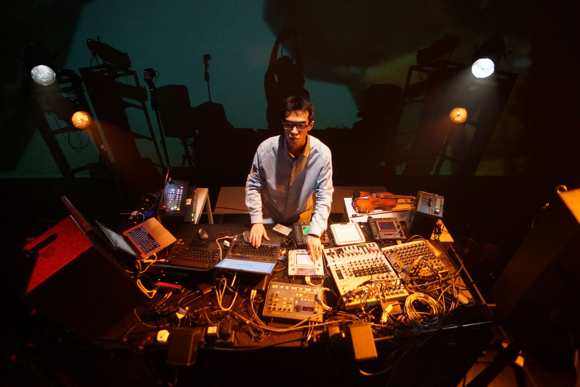 Choi Sai-ho surrounded by the banks of equipment he uses to create his music and visuals. 