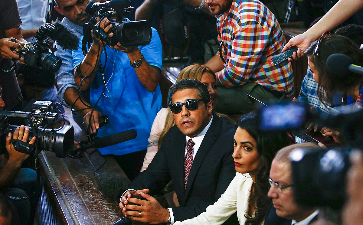 Al Jazeera journalist Mohammed Fahmy talks to the press ahead of his verdict at a courtroom in Cairo flanked by his wife Marwa and human rights lawyer Amal Clooney (foreground) . Photo: Xinhua