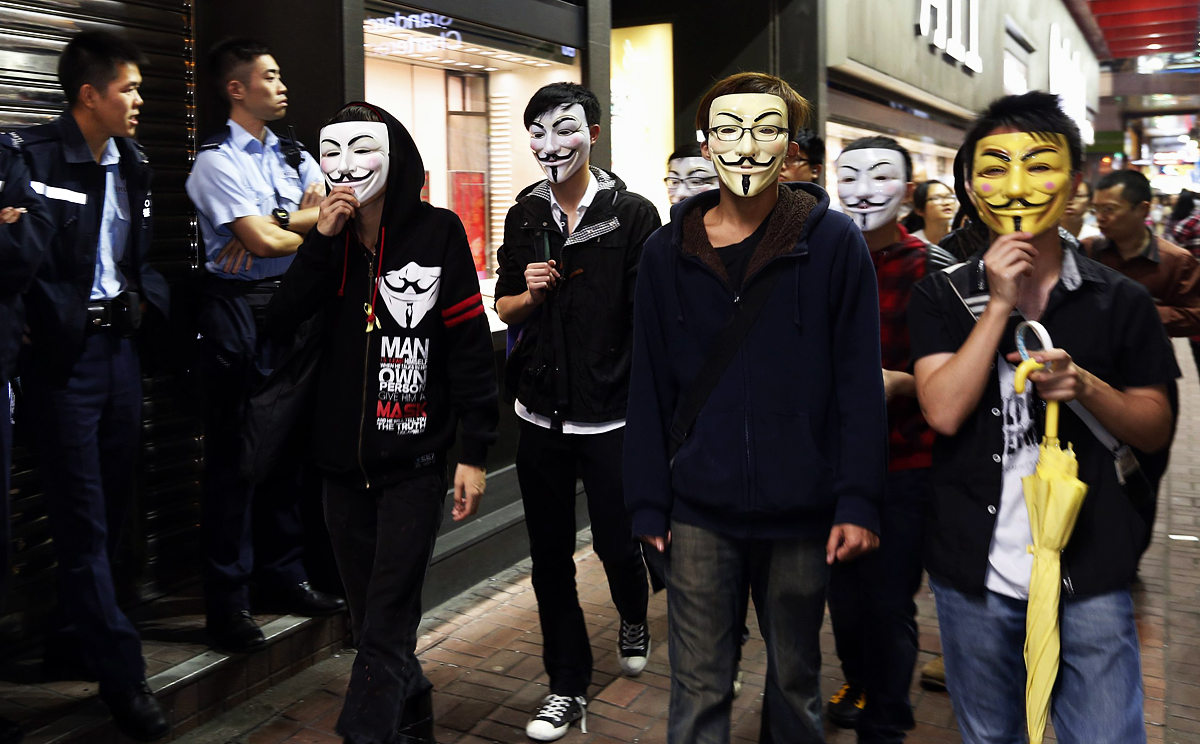 Pro-democracy protesters wearing Guy Fawkes masks walk past policemen on an occupied road in Mong Kok on Guy Fawkes Night last year. Photo: Reuters