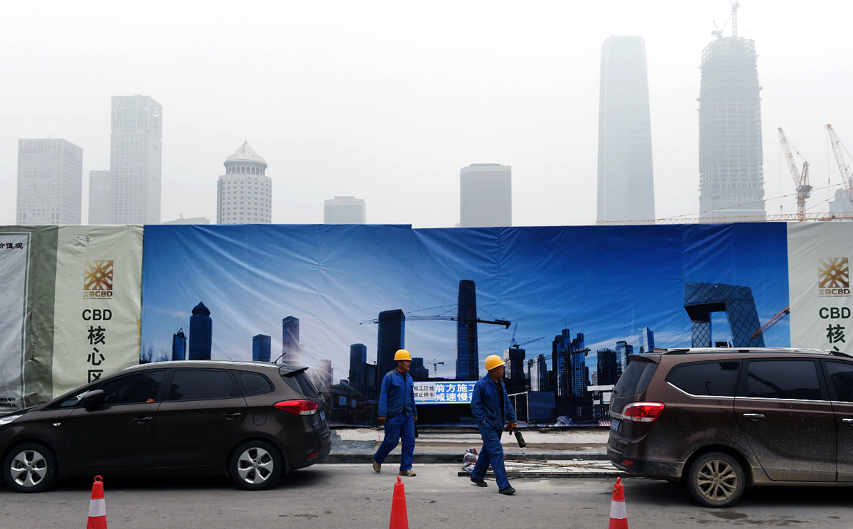 Workers walk past a billboard display showing a scene of Central Business District, as pollutant haze shrouds the skyline of Beijing. China is the world's biggest source of climate-changing gases. Photo: AP