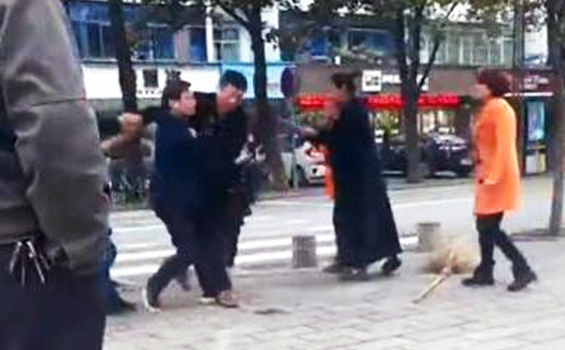 The attacker is held back by bystanders in Zhijiang city in Hubei province. The cleaner was sent to hospital, the police said. Photo: SCMP Pictures