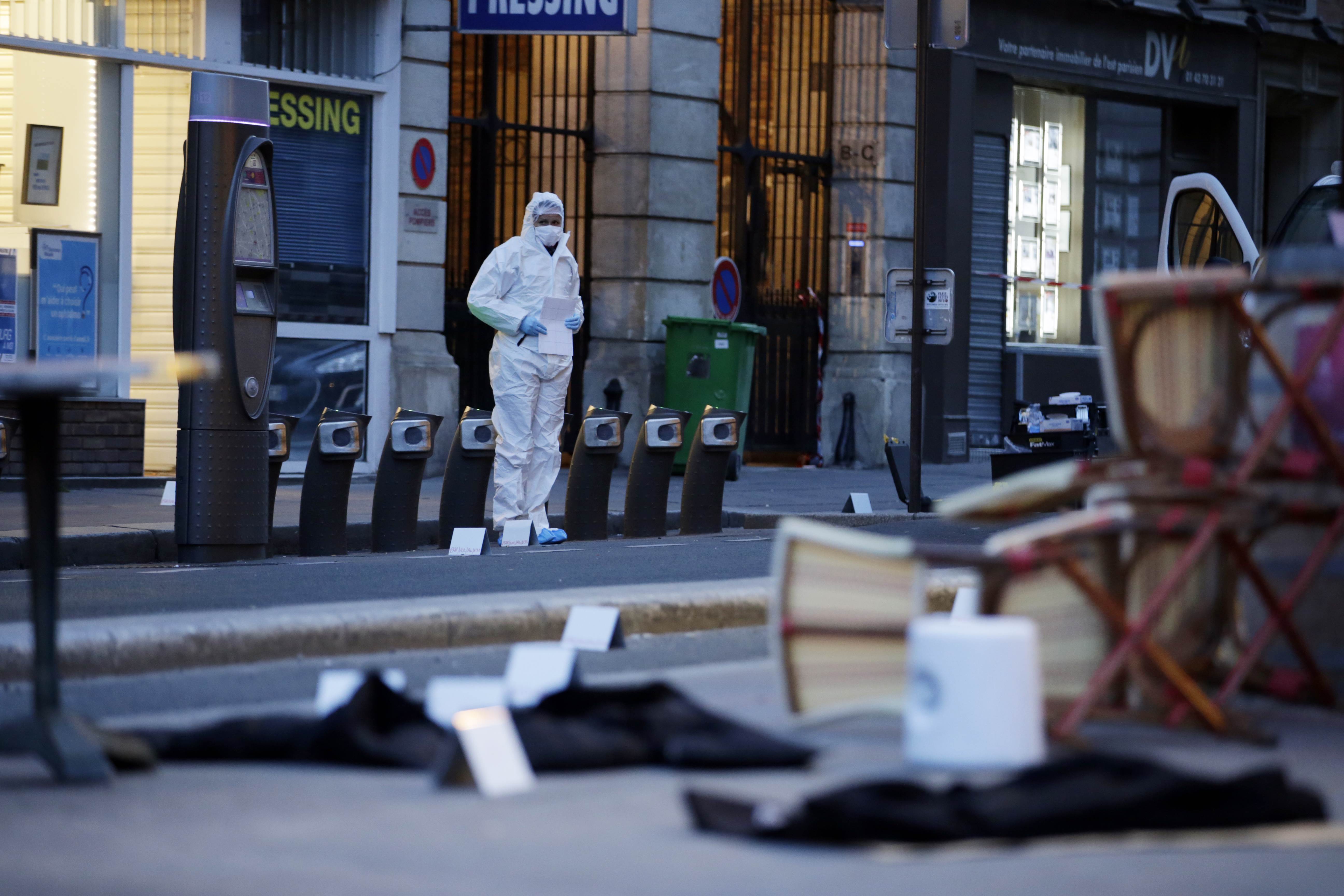 A forensic scientist inspects outside of the Cafe Bonne Biere on Rue du Faubourg du Temple in Paris following a series of coordinated attacks in and around Paris late Friday. photo: AFP