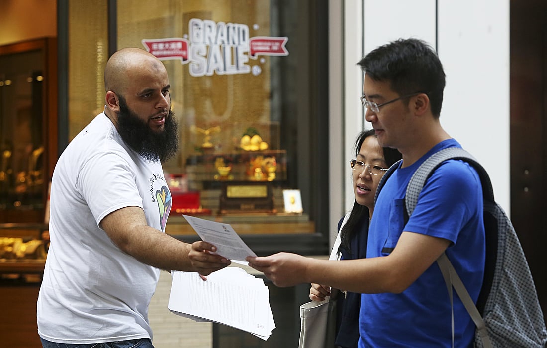 Adeel Malik hands out copies of the Muslim Council of Hong Kong's letter of peace condemning the terror attacks in Paris along Park Lane in Tsim Sha Tsui. Photo: Sam Tsang