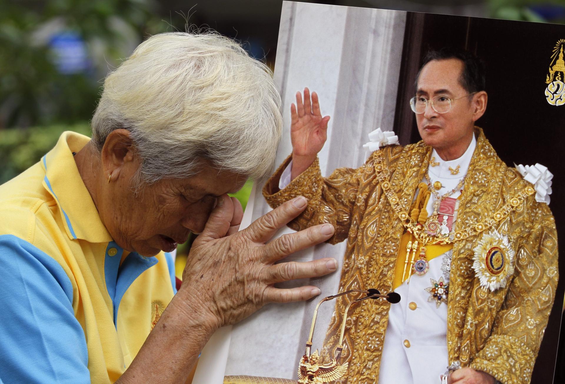 A Thai prays with a portrait of King Bhumibol Adulyadej to celebrate his 88th birthday at Siriraj Hospital in Bangkok yesterday. Photo: EPA
