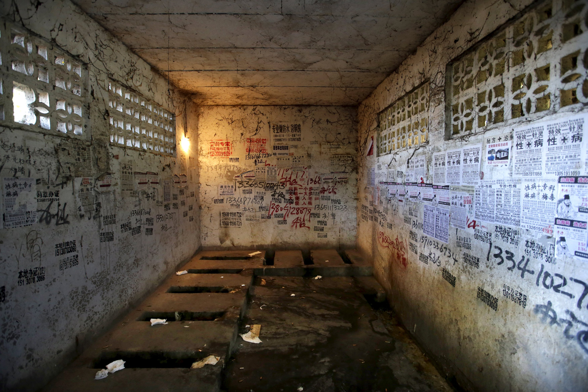 Posters, including those advertising treatments for sexually transmitted diseases, are stuck to the walls of a public toilet in a residential area for migrant workers in Shigezhuang village, Beijing. Photo: Reuters