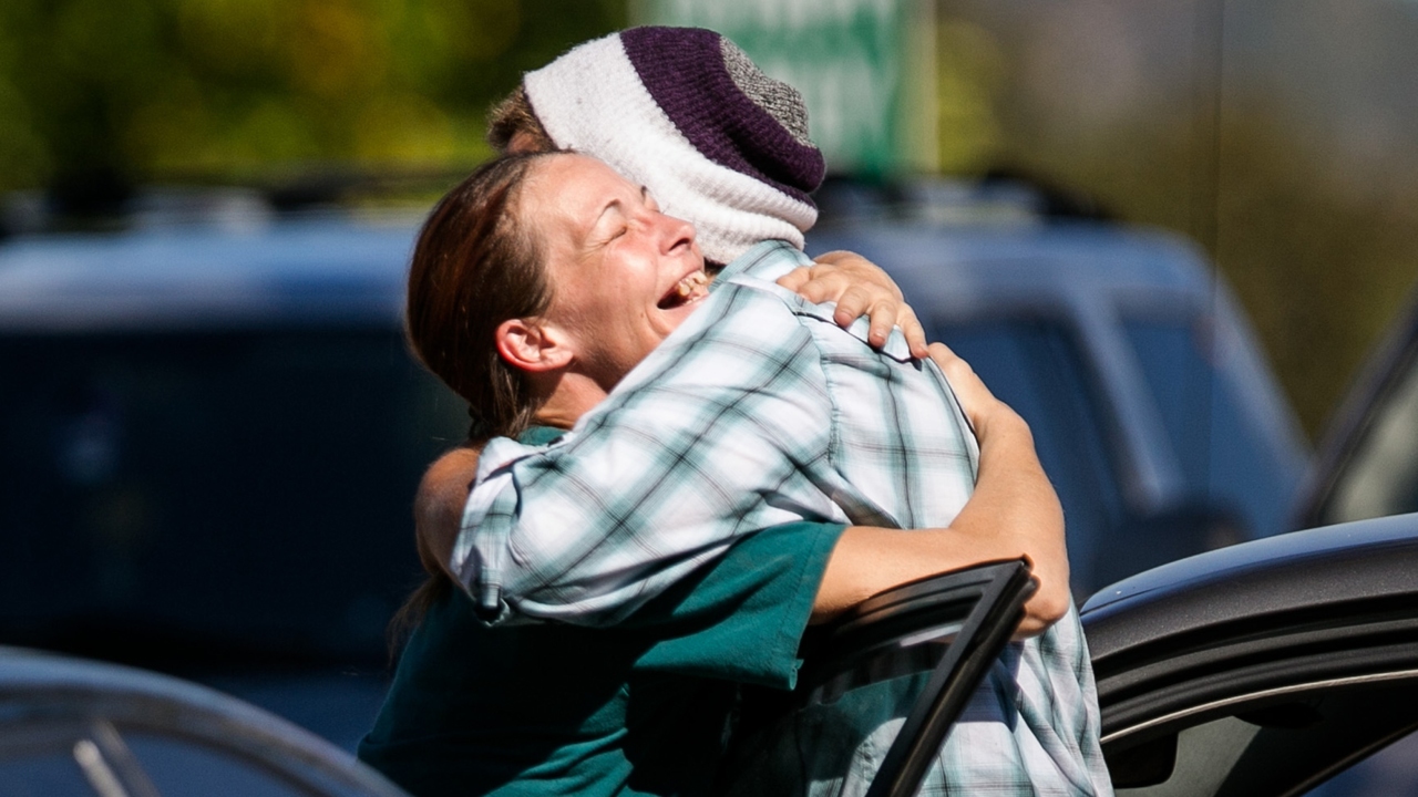 Mathew Downing, right, the "lucky survivor" of the Umpqua Community College mass shooting, hugs a friend as he arrives back on campus when it reopened last week. Photo: TNS