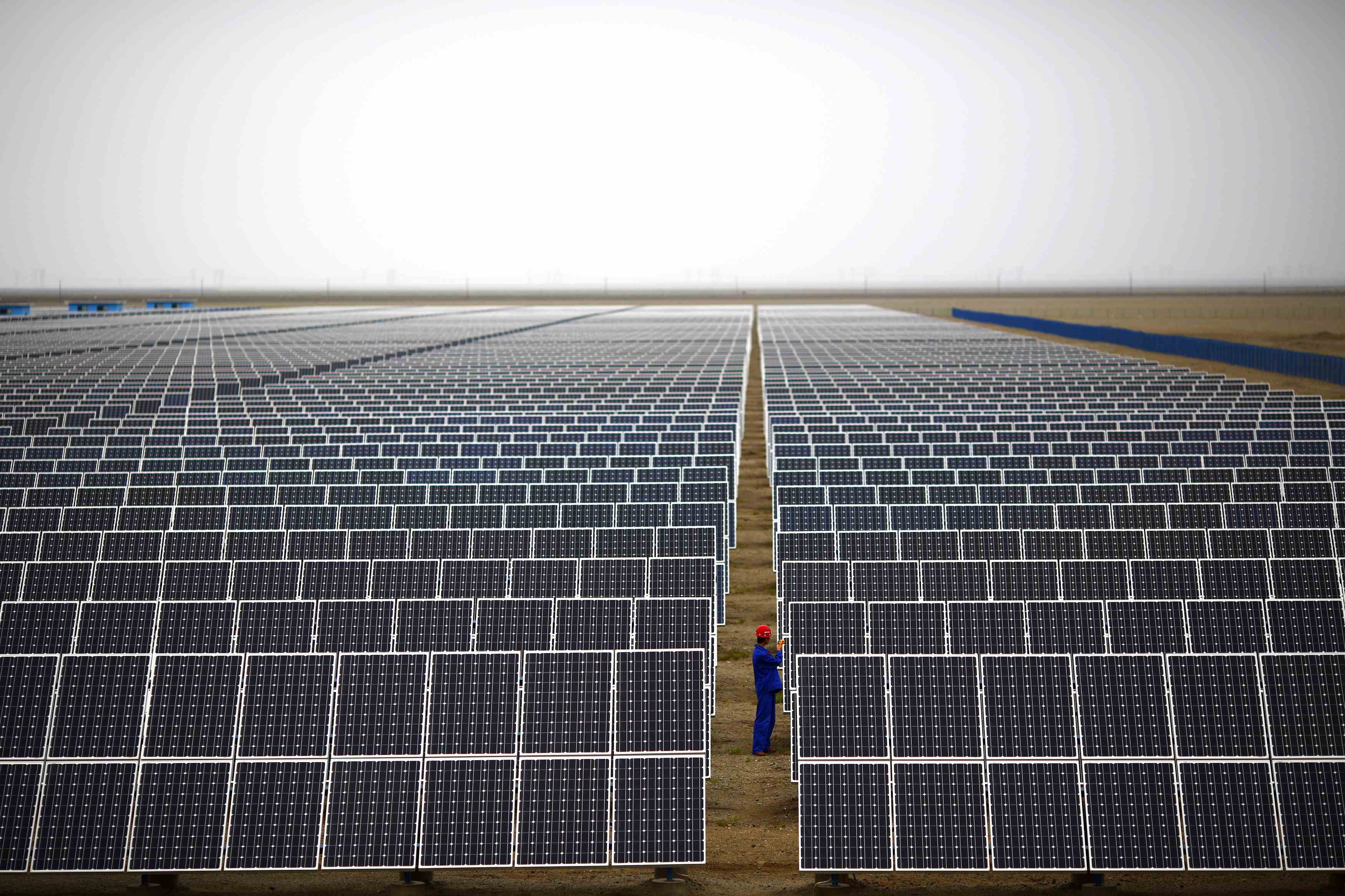 A worker inspects solar panels at a solar farm in Dunhuang, 950km (590 miles) northwest of Lanzhou, Gansu Province September 16, 2013. China's solar panel industry is showing signs of booming again after a prolonged downturn - raising fears of another bust when the splurge of public money that is driving a spike in demand dries up. Lured by generous power tariffs and financing support to promote renewable energy, Chinese firms are racing to develop multi-billion dollar solar generating projects in the Gobi desert and barren hills of China's vast north and northwest. Picture taken on September 16, 2013. REUTERS/Carlos Barria (CHINA - Tags: BUSINESS ENERGY)
