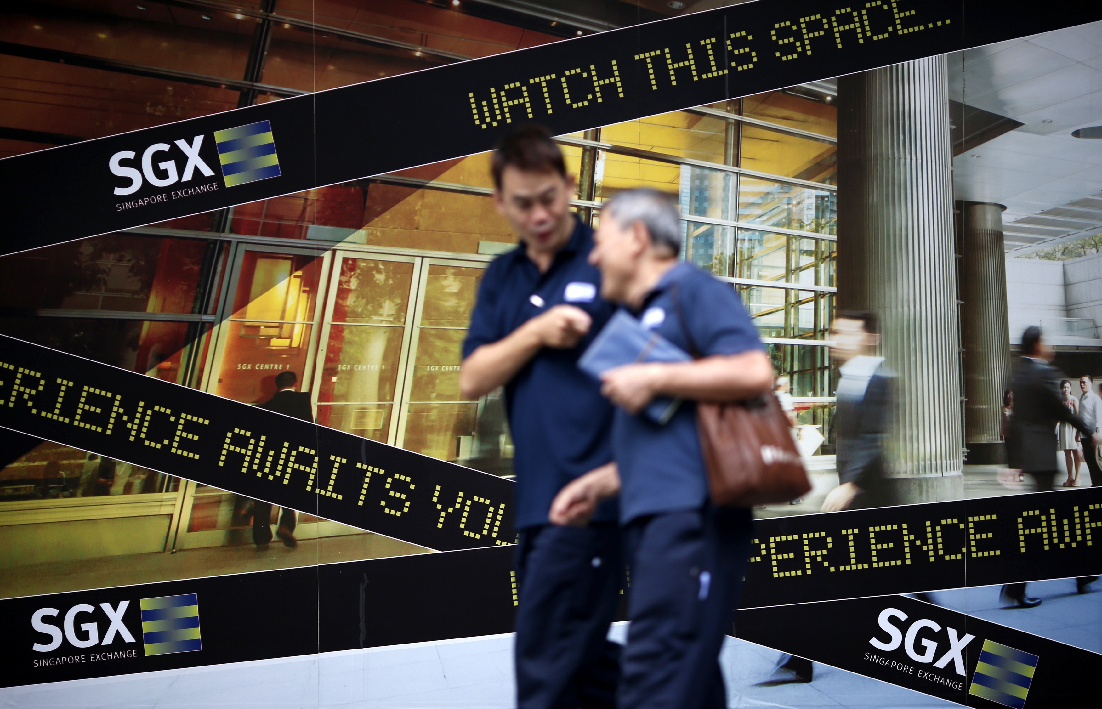 People walk past a logo of the Singapore Stock Exchange (SGX) outside its premises in the financial district of Singapore in this April 23, 2014 file photo. To match SGX-OUTLOOK/ Picture taken April 23, 2014. REUTERS/Edgar Su/Files (SINGAPORE - Tags: BUSINESS LOGO)