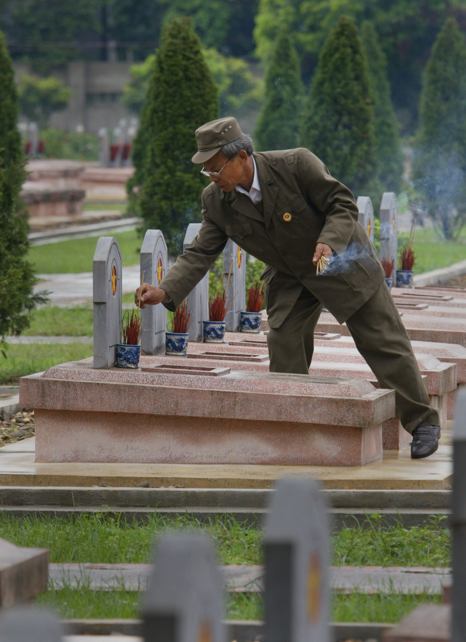 A Vietnamese war veteran places incense on graves of soldiers who died fighting the French in the historic city of Dien Bien Phu May 5, 2004. Vietnam is gearing up to commemorate the May 7, 1954 anniversary when Viet Minh forces overran the French garrison at Dien Bien Phu after a 56-day seige, forcing the French government to abandon its colonial control of Indochina. REUTERS/Bob Strong