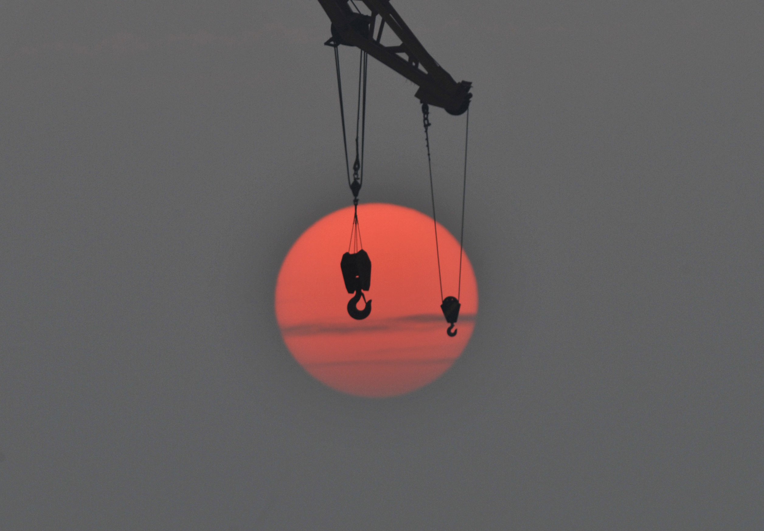 The hooks of a crane are pictured in front of the setting sun, at a port in Qingdao, Shandong province, China, October 14, 2015. China's economic planner said it approved 218 fixed-asset projects worth 1.81 trillion yuan ($285.3 billion) in the first nine months of the year, as Beijing looks to drive infrastructure investment to support slowing economic growth. Picture taken October 14, 2015. REUTERS/China Daily CHINA OUT. NO COMMERCIAL OR EDITORIAL SALES IN CHINA.