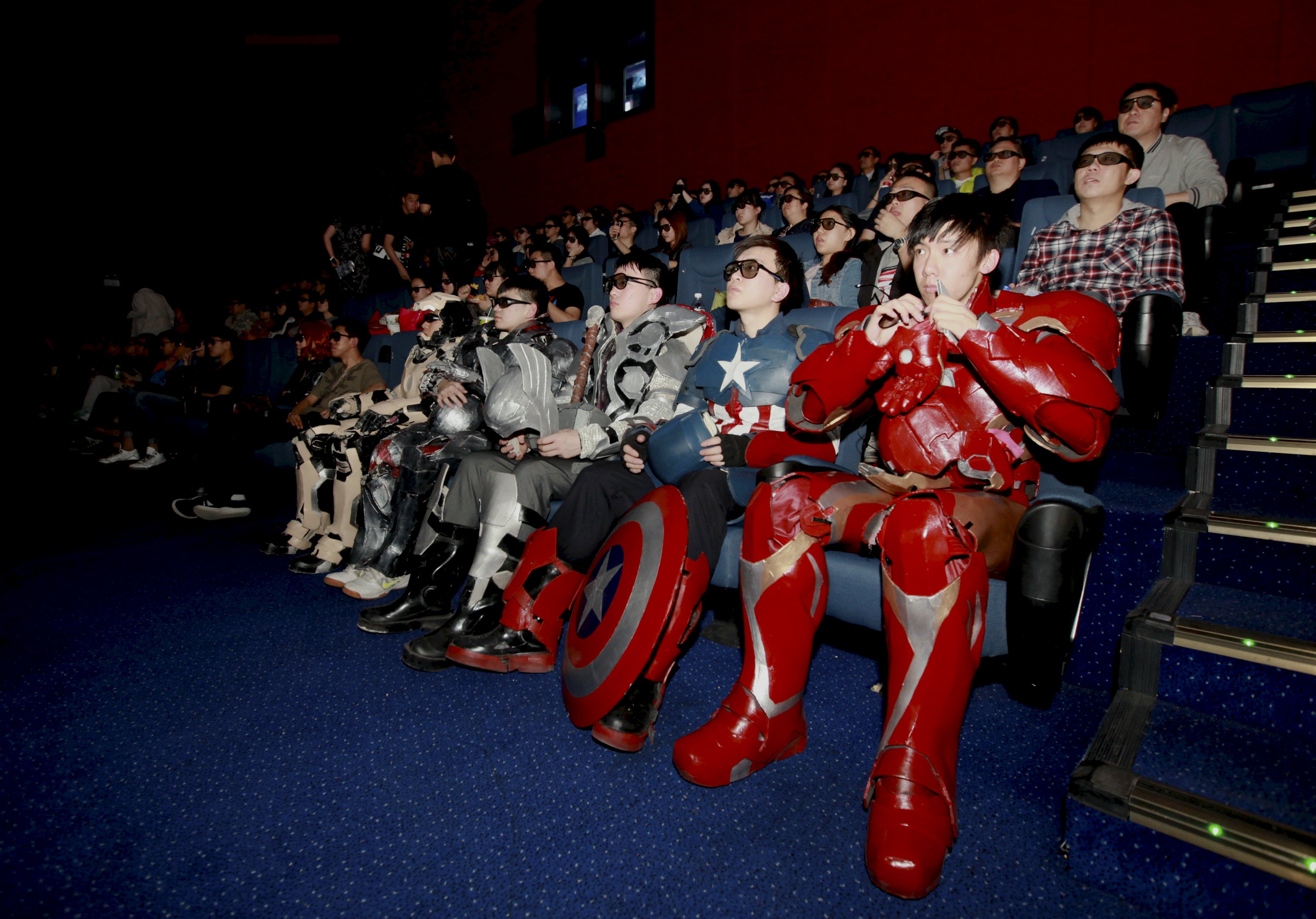 A group of fans dressed in homemade replica armours of "Avengers: Age of Ultron" movie characters, Iron Man, Captain America and Thor, watch the film in a theatre in Changchun, Jilin province, China, May 16, 2015. The group, led by college student Zu Bingqun, spent about 70,000 yuan to make the replica armours for all the main characters in the movie, local media reported. Picture taken May 16, 2015. REUTERS/Stringer ATTENTION EDITORS - CHINA OUT. NO COMMERCIAL OR EDITORIAL SALES IN CHINA