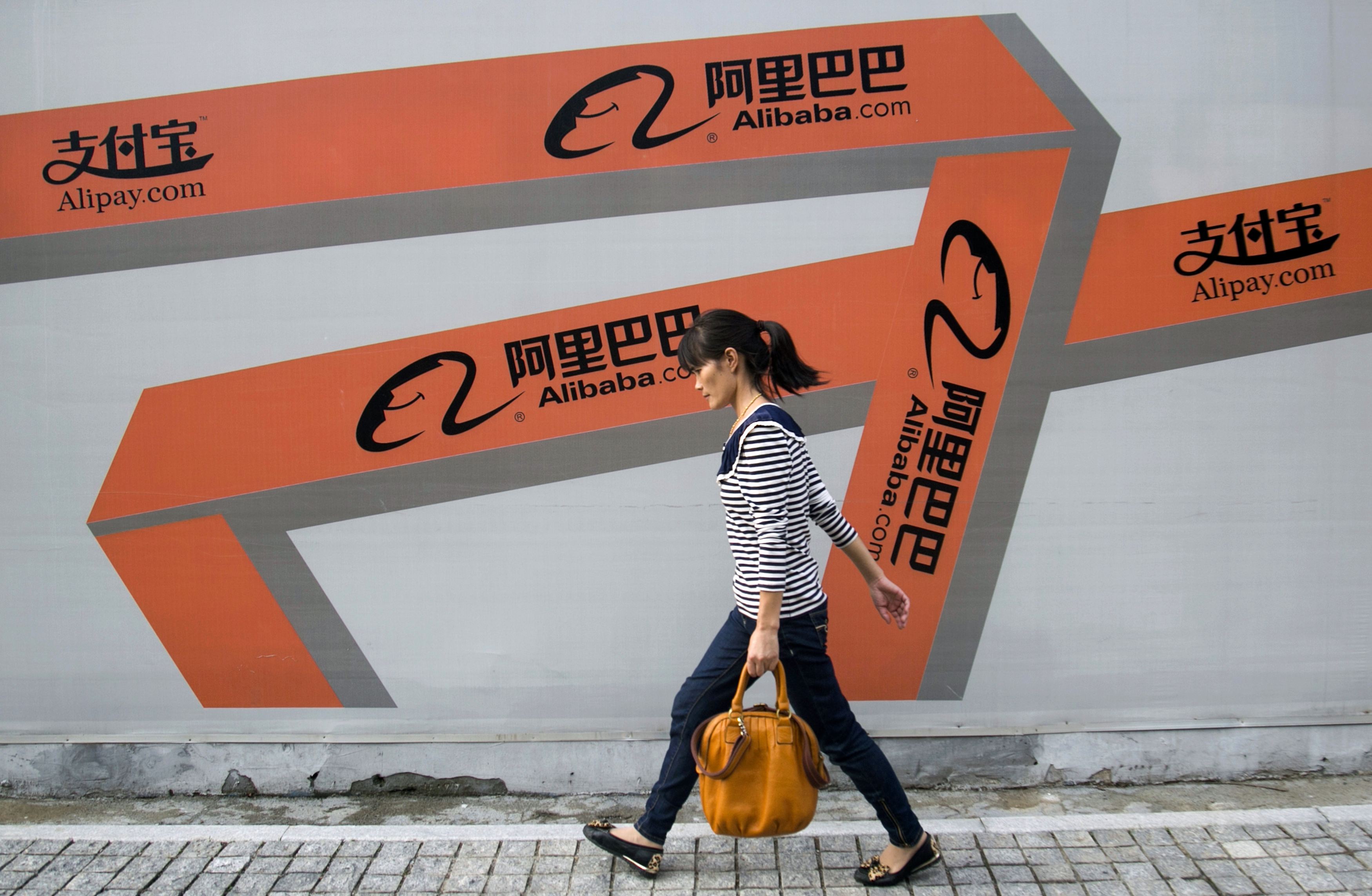 A woman walks past an Alibaba advertisement on a wall in Hangzhou, Zhejiang province, in this file picture taken September 26, 2013. Alibaba Group Holding will not change its partnership structure in order to list on the Hong Kong stock exchange, Executive Vice Chairman Joe Tsai told Reuters in an exclusive interview in Hong Kong on March 12, 2014. To match Interview ALIBABA-IPO/TSAI REUTERS/Chance Chan/Files (CHINA - Tags: BUSINESS LOGO) - RTX14096 CHINA OUT. NO COMMERCIAL OR EDITORIAL SALES IN CHINA