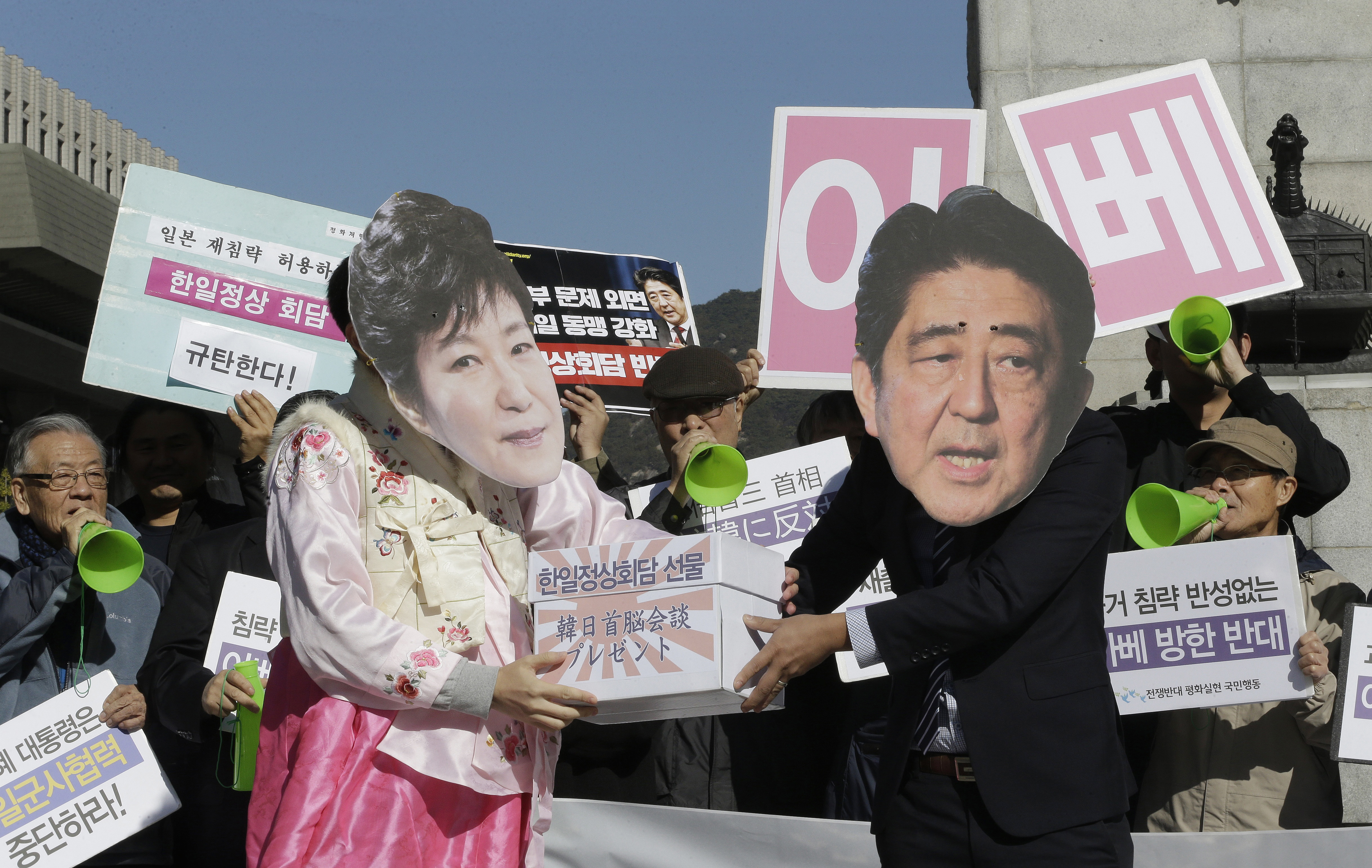 Protesters wearing masks of Japanese Prime Minister Shinzo Abe, right, and South Korean President Park Geun-hye stage a rally against Abe's planned visit in Seoul, South Korea, Friday, Oct. 30, 2015. Abe and Chinese Premier Li Keqiang will visit Seoul for their trilateral summit with Park. The letters on the cards read "Oppose Abe's visit." (AP Photo/Ahn Young-joon)