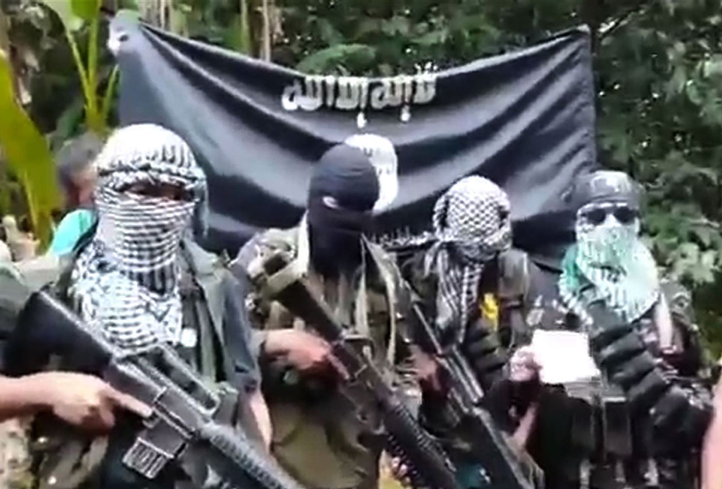 This undated image grab taken on October 13, 2015 from a video uploaded on YouTube shows gunmen standing behind three foreign men (not pictured) and a Filipina (not pictured) who were kidnapped last month in the southern Philippines. Gunmen raided a luxury marina near the major southern city of Davao on September 21, abducting the Norwegian owner of the resort, two Canadian tourists and one of their girlfriends. No group immediately claimed responsibility but the video uploaded on YouTube on October 13 appeared to confirm it was the Abu Sayyaf, which has a long history of kidnappings-for-ransom in the southern Philippines. In the video, the three foreigners appealed for Philippine authorities to halt military assaults against the gunmen. AFP PHOTO / YOUTUBE ---EDITORS NOTE--- RESTRICTED TO EDITORIAL USE - MANDATORY CREDIT "AFP PHOTO / YOUTUBE" - NO MARKETING NO ADVERTISING CAMPAIGNS - DISTRIBUTED AS A SERVICE TO CLIENTS - NO ARCHIVES