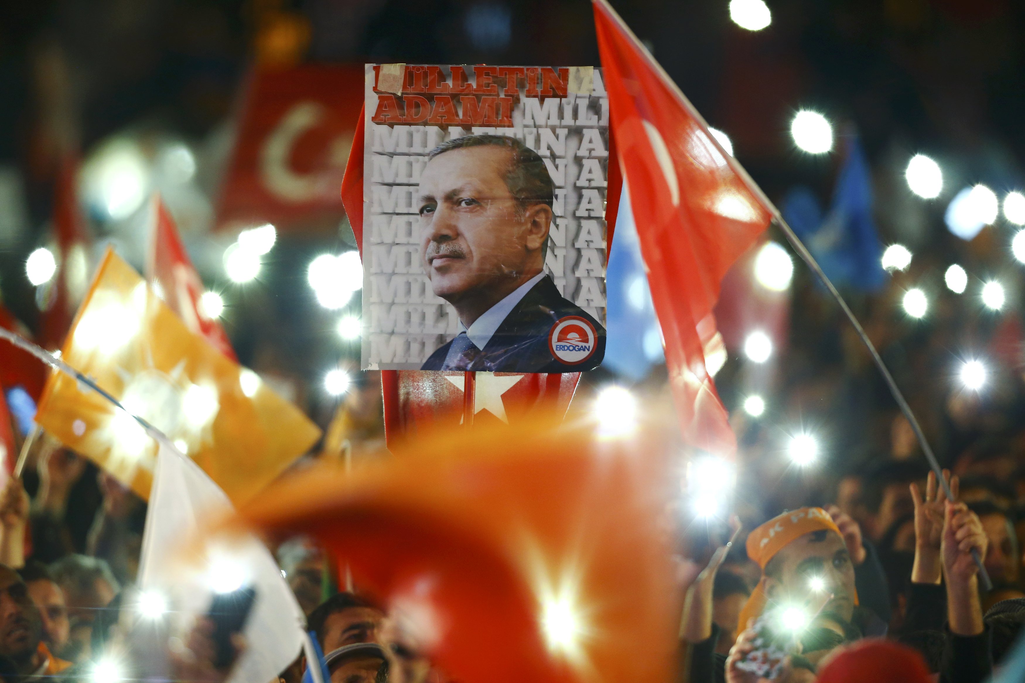 People wave flags and hold a portrait of Turkish President Tayyip Erdogan as they wait for the arrival of Prime Minister Ahmet Davutoglu in Ankara, Turkey November 2, 2015. Davutoglu described the outcome of a general election which swept his AK Party back to a parliamentary majority on Sunday as a victory for democracy. REUTERS/Umit Bektas