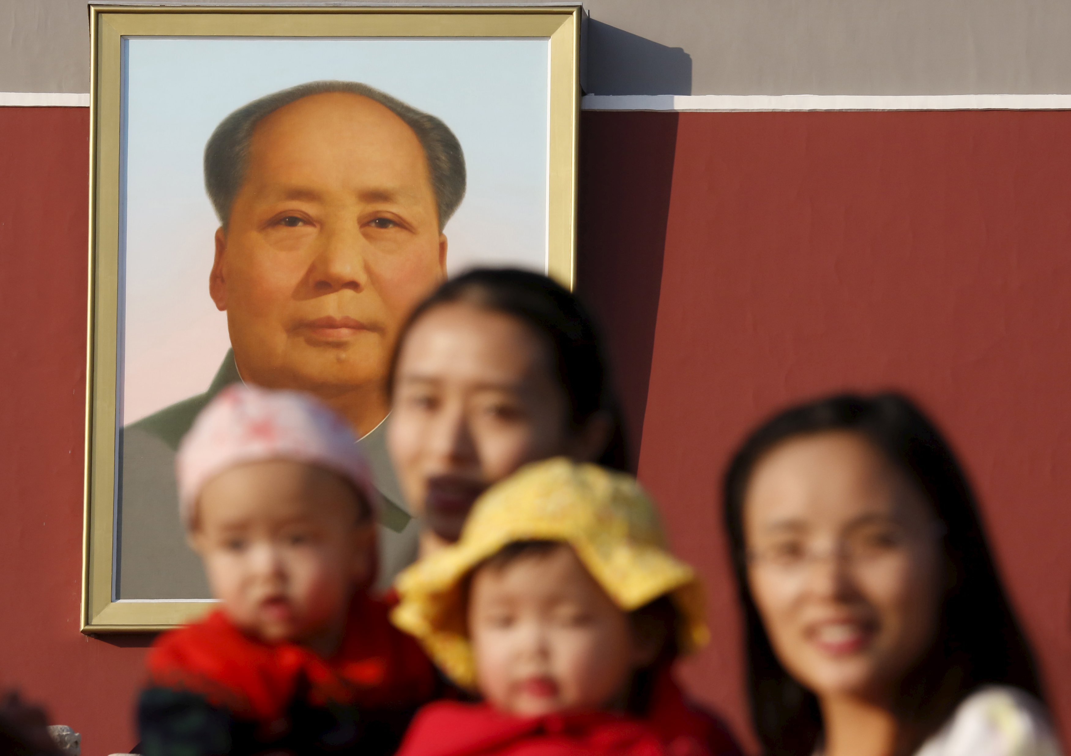 Two women and their babies pose for photographs in front of the giant portrait of late Chinese chairman Mao Zedong on the Tiananmen Gate in Beijing November 2, 2015. China must continue to enforce its one-child policy until new rules allowing all couples to have two children go into effect, the top family planning body said. The ruling Communist Party said last week that Beijing would loosen its decades-old one-child policy. The plan for the change must be approved by the rubber-stamp parliament during its annual session in March. REUTERS/Kim Kyung-Hoon