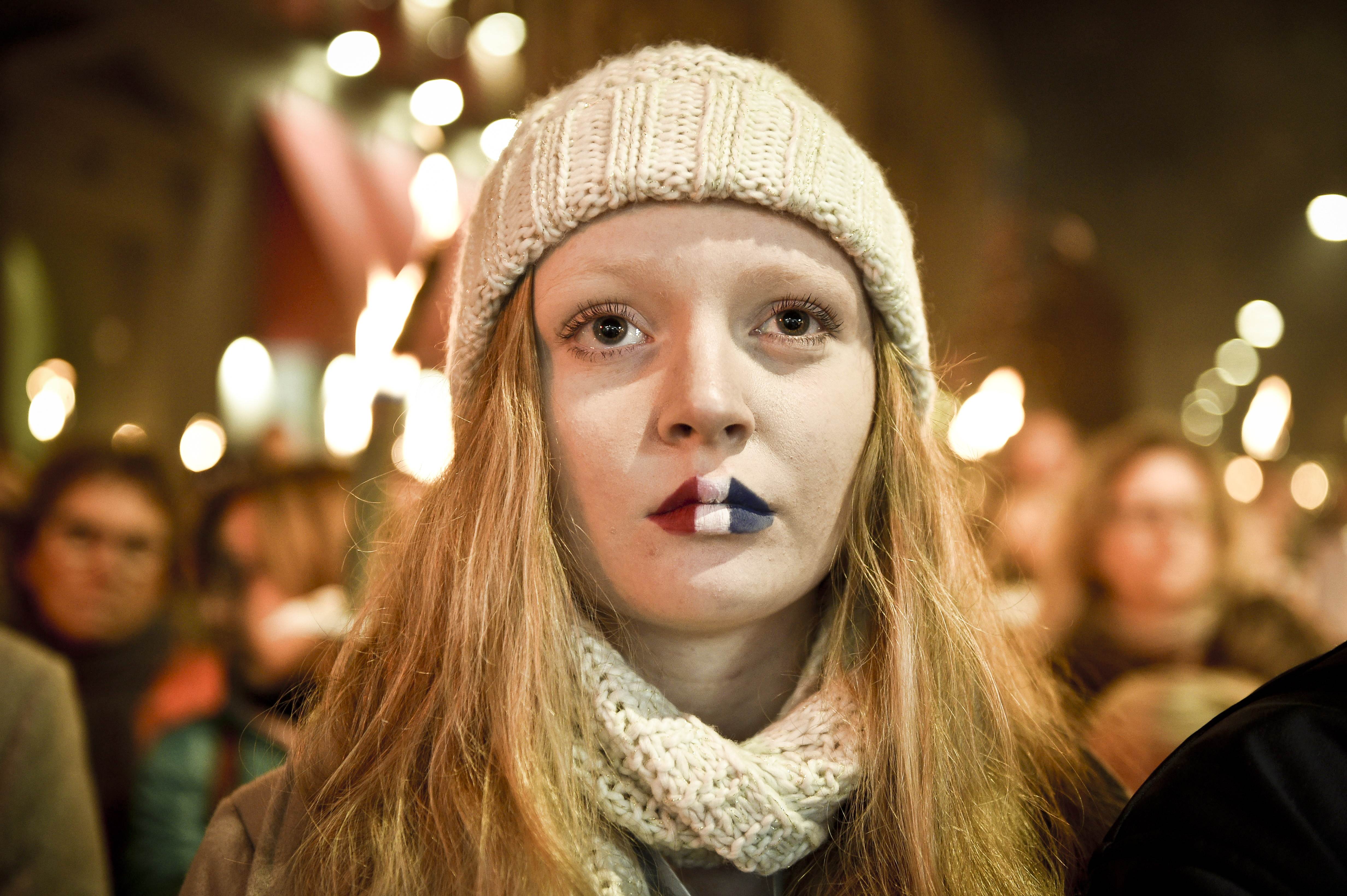 A girl with lips painted in French tricolor attends a vigil in memory of Paris attack victims in front of the French Embassy on November 15, 2015 in Copenhagen. Up to 20,000 people, among them Prime Minister Lars Lokke Rasmussen, gathered for a candlelight vigil at the gates of the French embassy in Copenhagen Sunday to mourn the victims of the Paris attacks, police said. AFP PHOTO / Nils Meilvang / SCANPIX DENMARK / NILS MEILVANG +++ DENMARK OUT