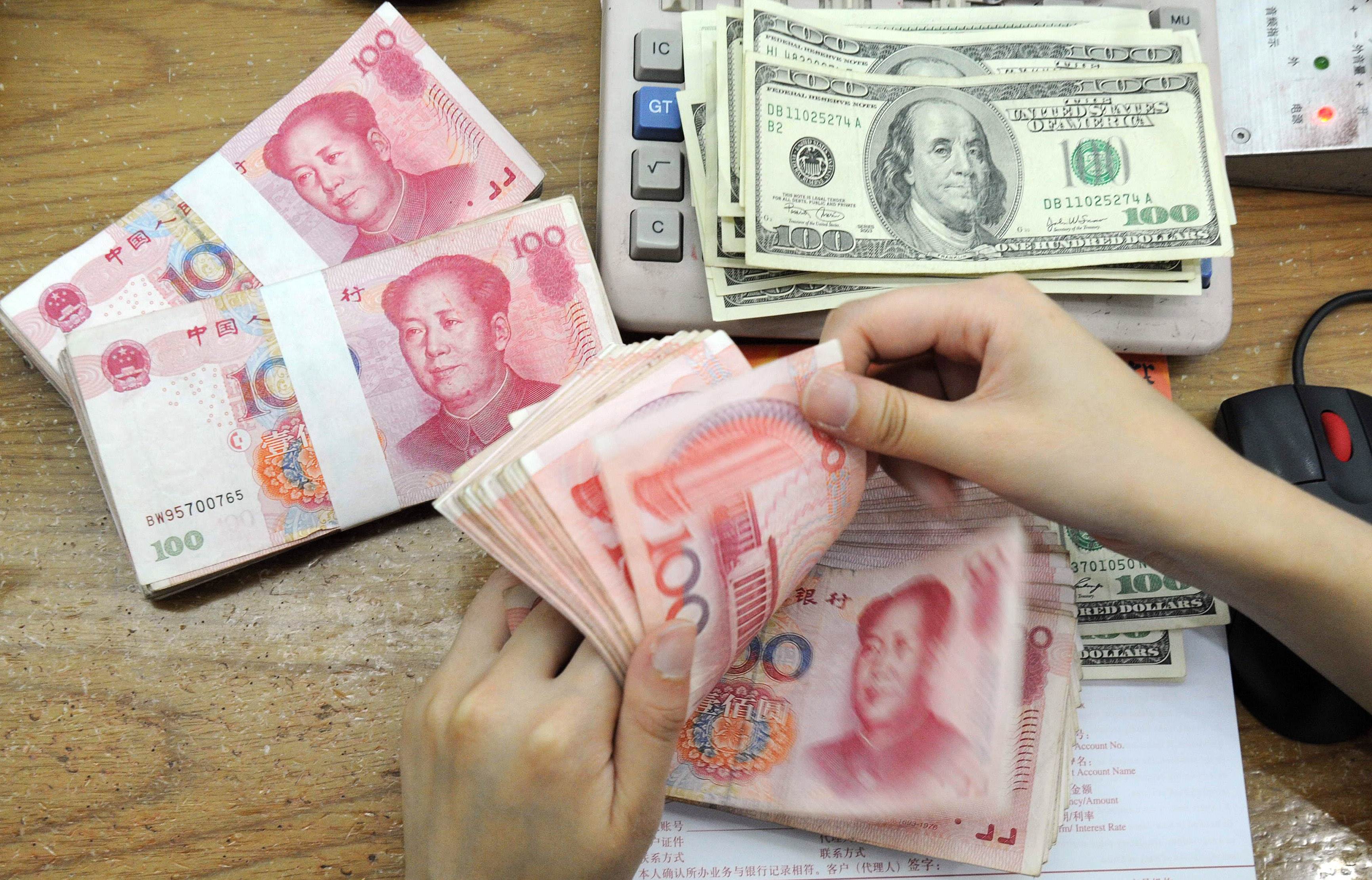 (FILES) This file photo taken on September 30, 2010 shows a Chinese bank worker counting 100-yuan notes and US 100-dollar bills at a bank counter in Hefei, in east China's Anhui province. China's central bank on August 14, 2015 strengthened the yuan currency against the US dollar by 0.05%, the national foreign exchange market said, ending three days of falls after a surprise devaluation. CHINA OUT AFP PHOTO / FILES