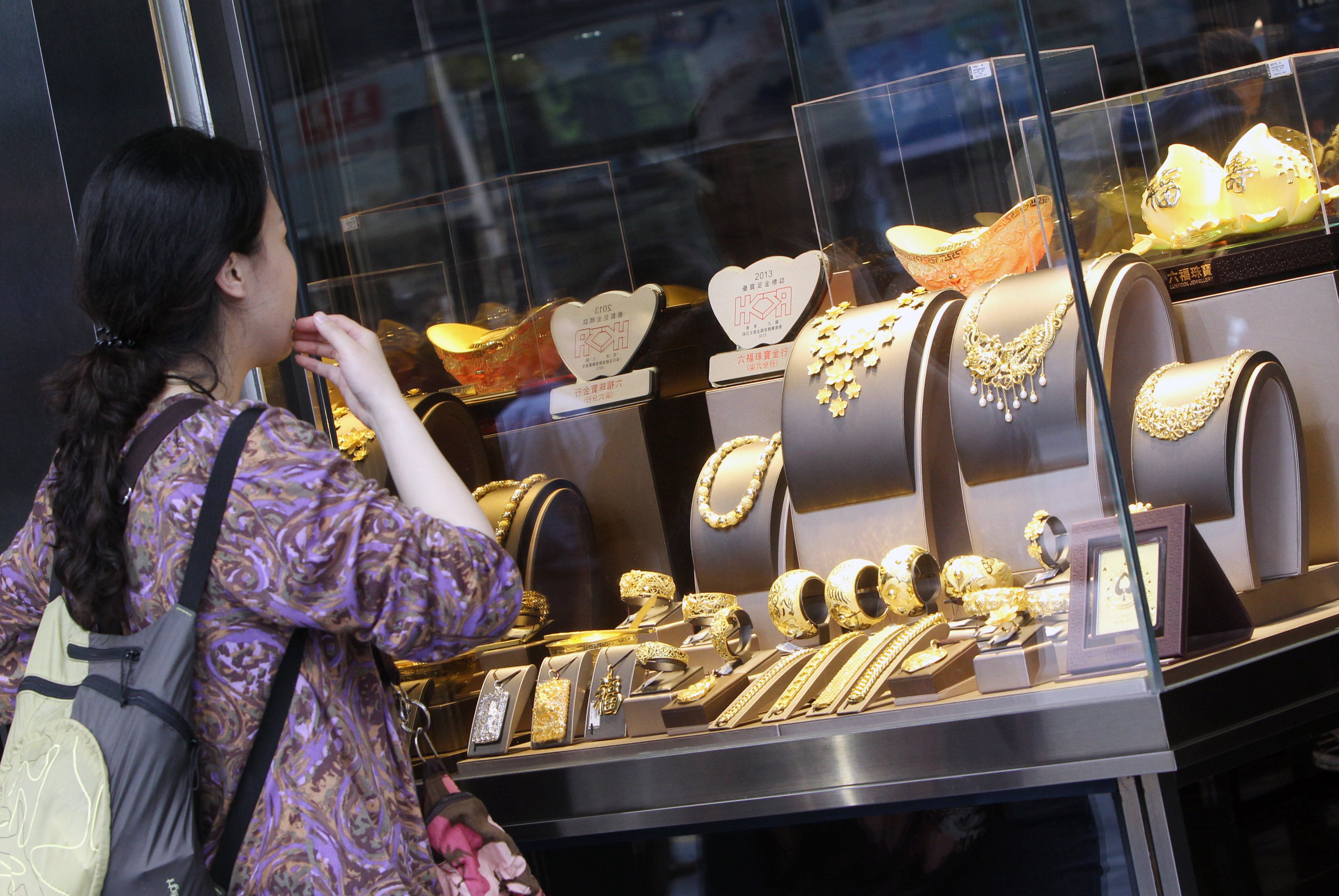 A woman looks at gold products in a jewellery shop in Tsim Sha Tsui. Gold prices were under pressure in Asian trade after the precious metal suffered its biggest dive in more than 30 years. 16APR13