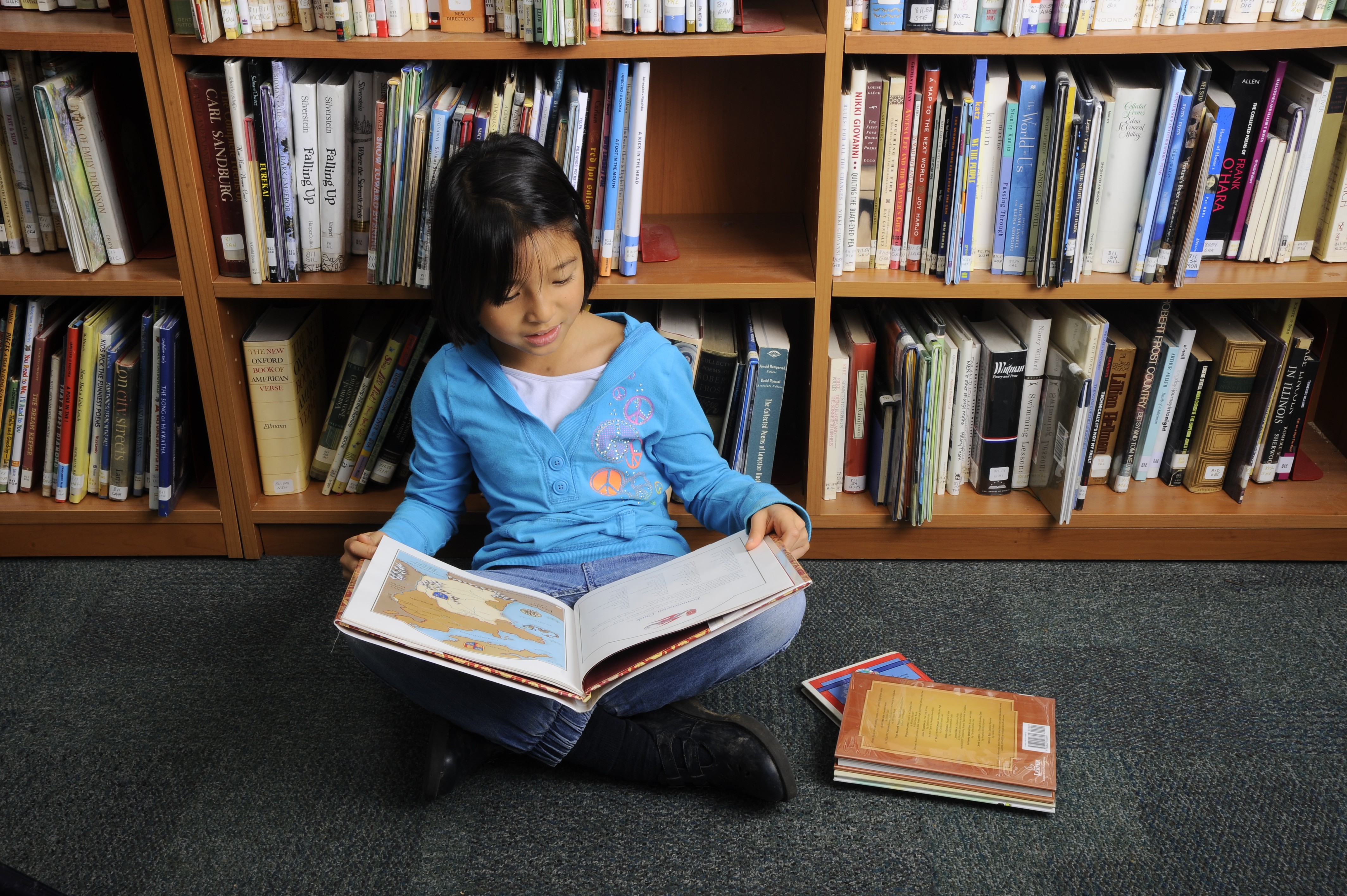 8 year old asian girl looks through books on a shelf in a library. --- Image by © Richard Hutchings/Corbis [01DECEMBER2015 FEATURES LIFE]
