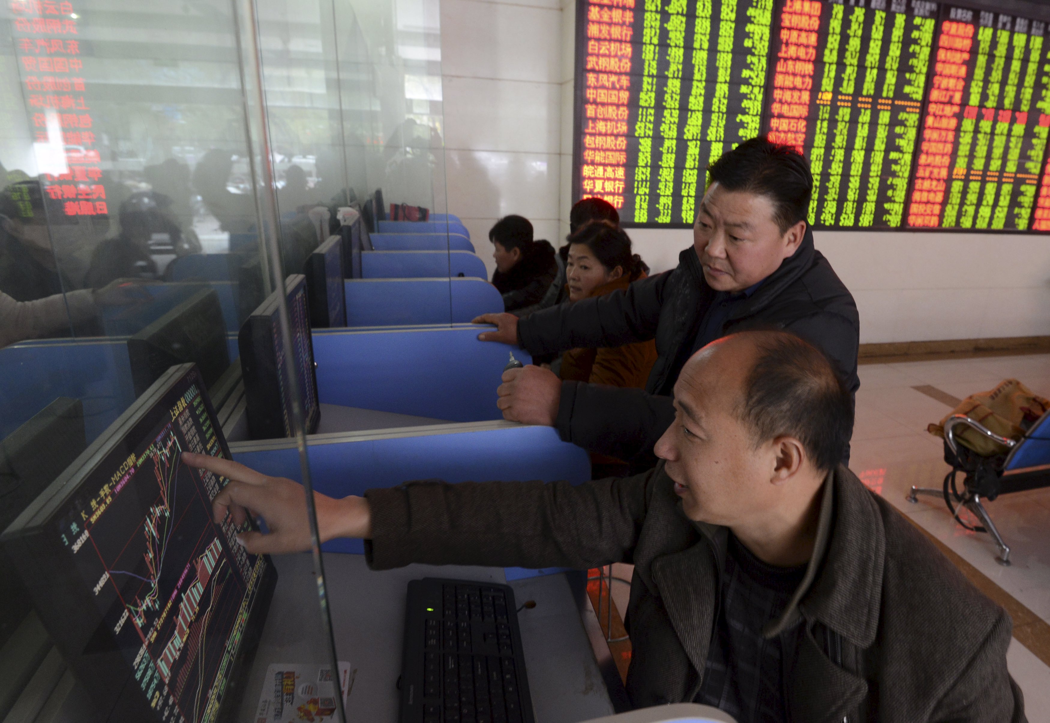 Investors talk as they look at a computer screen showing stock information at a brokerage house in Fuyang, Anhui province, China, November 27, 2015. China stocks tumbled more than 5 percent on Friday in their biggest one-day loss in three months as a fresh regulatory crackdown and deteriorating profits triggered profit-taking after a recent rebound. REUTERS/China Daily CHINA OUT. NO COMMERCIAL OR EDITORIAL SALES IN CHINA