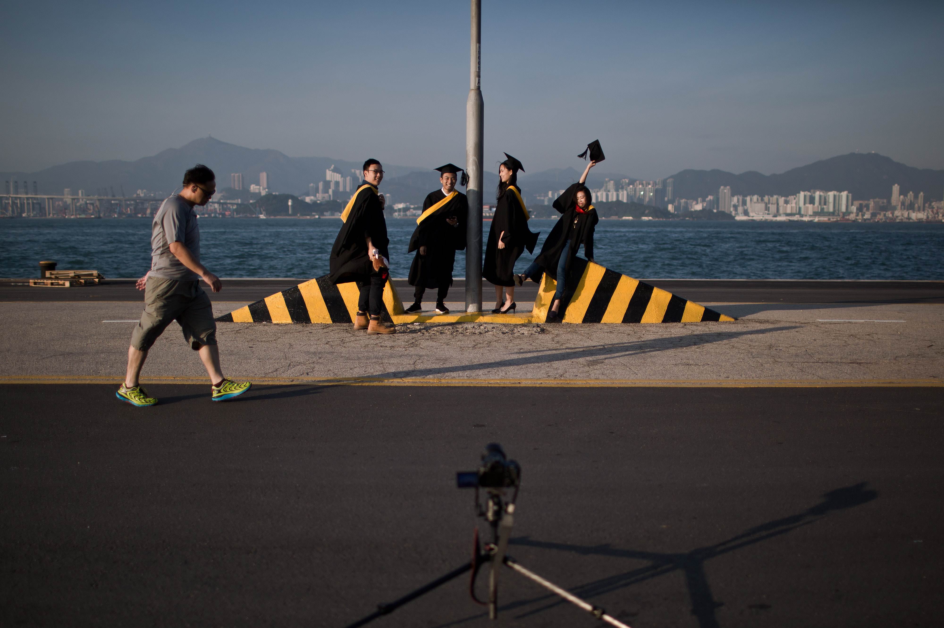 University students pose for graduation photographs on a public pier in Hong Kong on November 28, 2015. AFP PHOTO / DALE DE LA REY