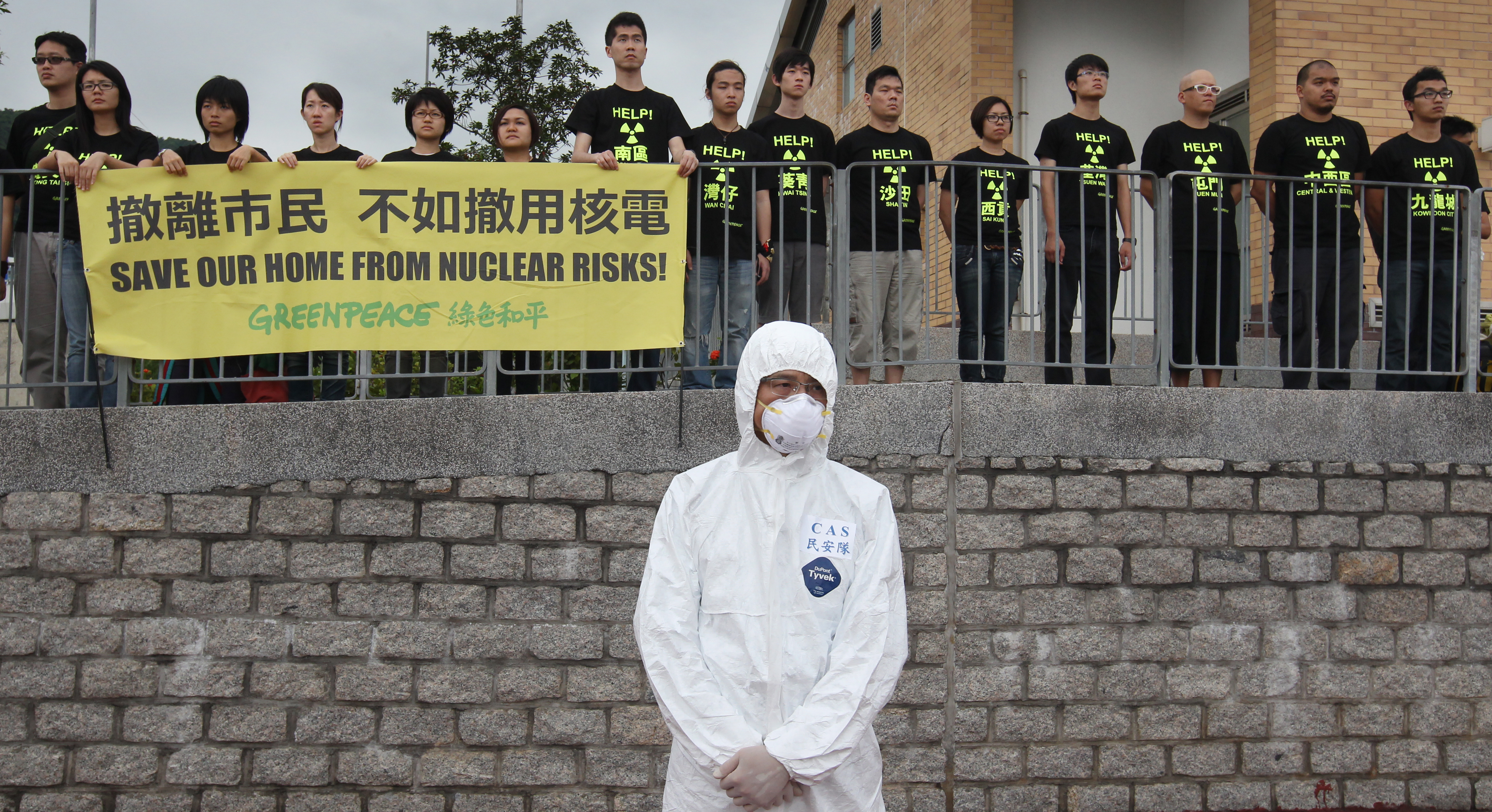 A rescue worker wearing a protective suit stands in front of protesters from Greenpeace near the Ma Liu Shui Ferry Pier during an evacuation drill at Daya Bay Nuclear Plant, as they demand the Hong Kong government to phase out nuclear plants, in Hong Kong Thursday, April 26, 2012. The Hong Kong government conducted the major interdepartmental exercise to prepare for a possible accident at the nuclear plant at Daya Bay in southern China, near Hong Kong. 26APR12