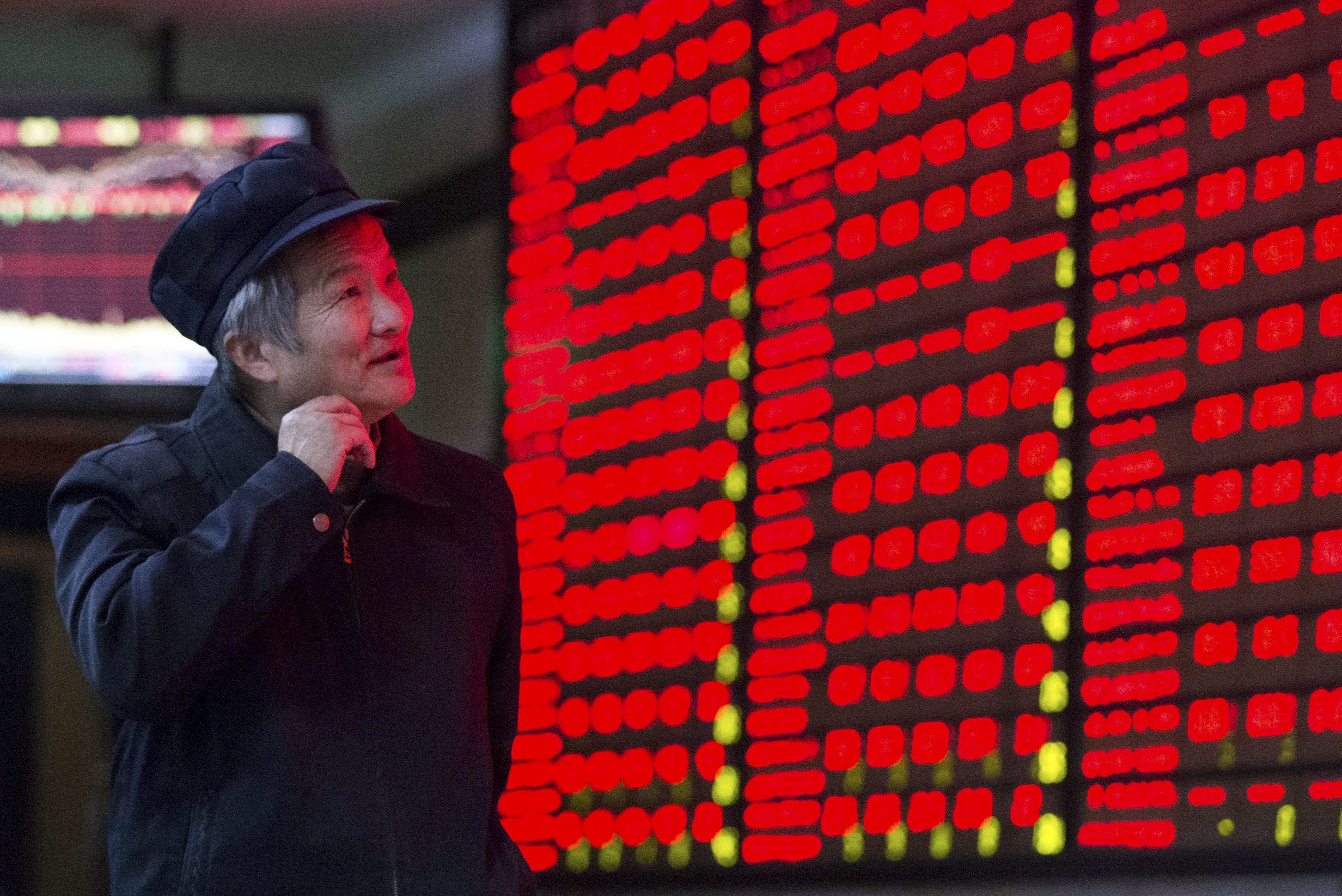 An investor looks at an electronic board showing stock information, filled with red colour indicating rising prices, at a brokerage house in Nanjing, Jiangsu province, China, December 3, 2015. REUTERS/China Daily CHINA OUT. NO COMMERCIAL OR EDITORIAL SALES IN CHINA
