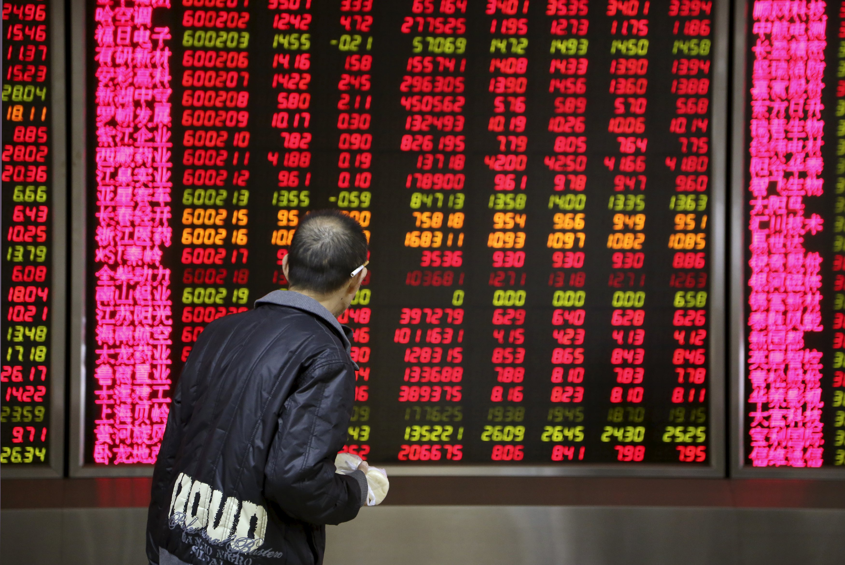 An investor walks past in front of an electronic board showing stock information at a brokerage house in Beijing, China, November 17, 2015. After a solid performance in morning trade, China stocks lost momentum and ended Tuesday flat as small caps slumped on profit-taking, reflecting how market sentiment remained fragile. REUTERS/Li Sanxian CHINA OUT. NO COMMERCIAL OR EDITORIAL SALES IN CHINA