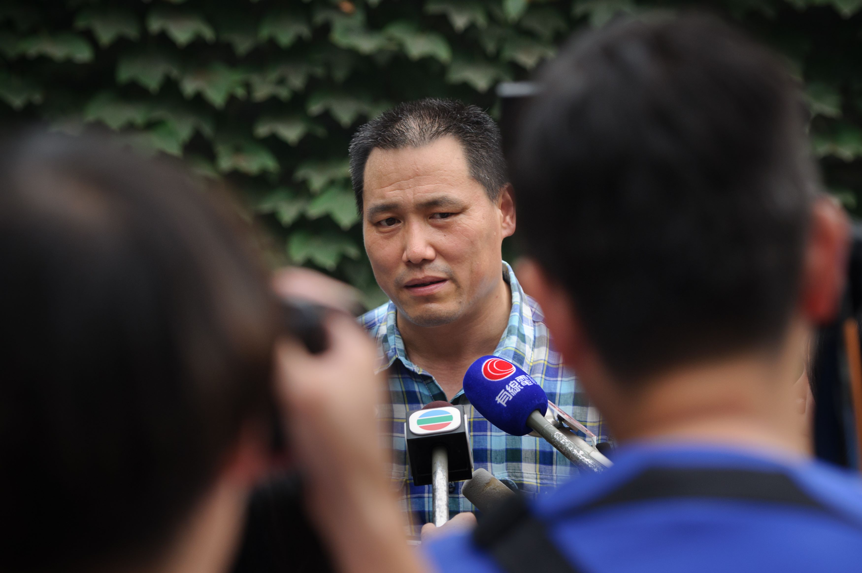 In a photo taken on July 20, 2012 human rights lawyer Pu Zhiqiang (C) talks to the media at the compound of dissident artist Ai Weiwei in the Caochangdi district of Beijing. One of China's most celebrated human rights lawyers went on trial December 14, 2015 over online comments critical of the ruling Communist Party, as police scuffled with supporters and journalists gathered outside the courthouse. Pu Zhiqiang, who has represented labour camp victims and dissident artist Ai Weiwei, was detained a year and a half ago in a nationwide crackdown on dissent. He faces a maximum of eight years in jail on charges of "inciting ethnic hatred" and "picking quarrels and provoking trouble", according to his lawyer Mo Shaoping. AFP PHOTO / Ed Jones