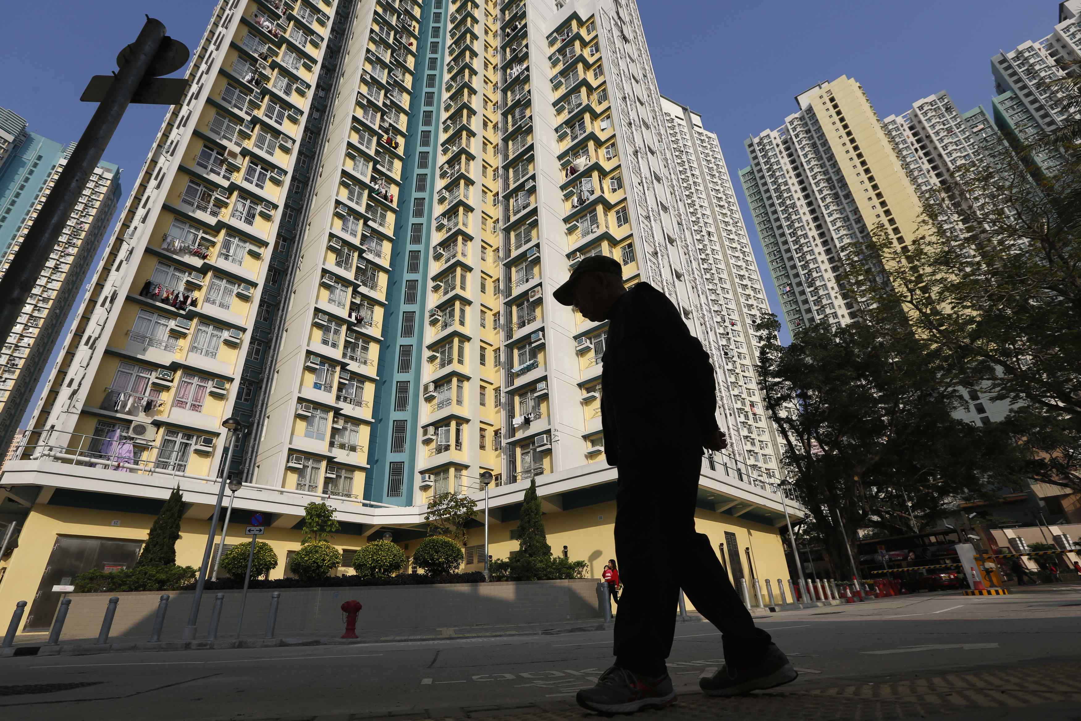 A man walks past public housing in Hong Kong January 16, 2013. Embattled Hong Kong leader Leung Chun-ying made his maiden policy speech on Wednesday unveiling policies aimed at reviving his battered reputation, such as increasing land supply to cool a hot property market, fighting pollution and boosting welfare. REUTERS/Tyrone Siu (CHINA - Tags: POLITICS BUSINESS REAL ESTATE SOCIETY)