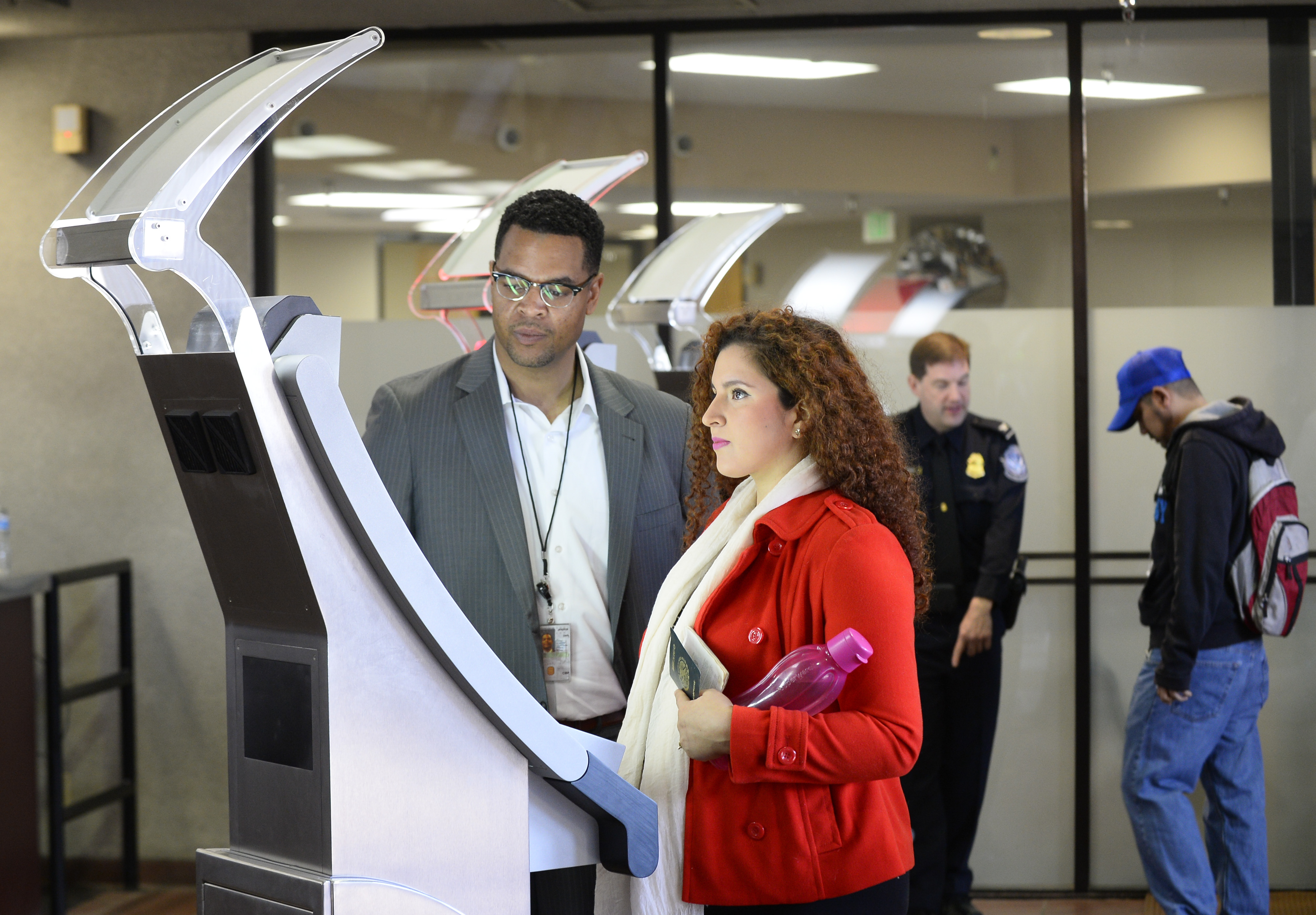 Contractor Dain Pettie, left, helps a pedestrian crossing from Mexico into the United States at the Otay Mesa Port of Entry have her facial features and eyes scanned at a biometric kiosk Thursday, Dec. 10, 2015, in San Diego. On Thursday, U.S. Customs and Border Protection began capturing facial and eye scans of foreigners entering the country at San Diego's Otay Mesa port of entry on foot. (AP Photo/Denis Poroy)