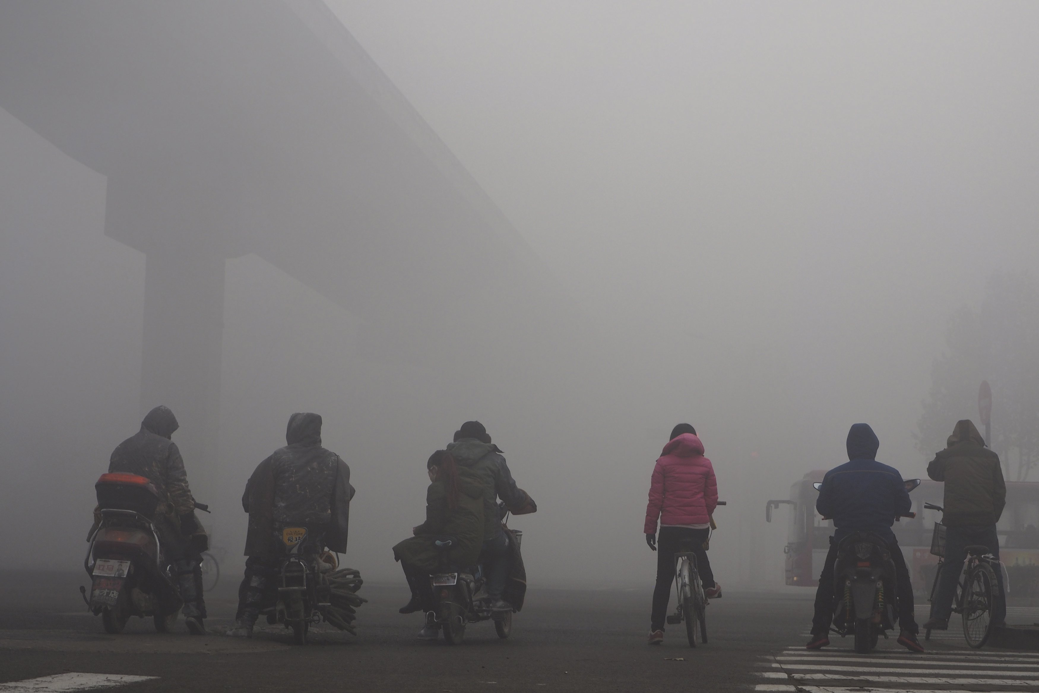 Residents on their bicycles and electric bikes wait for the traffic at an intersection amid heavy smog in Shijiazhuang, Hebei province, China, December 10, 2015. Picture taken December 10, 2015. REUTERS/Stringer ATTENTION EDITORS - THIS PICTURE WAS PROVIDED BY A THIRD PARTY. THIS PICTURE IS DISTRIBUTED EXACTLY AS RECEIVED BY REUTERS, AS A SERVICE TO CLIENTS. CHINA OUT. NO COMMERCIAL OR EDITORIAL SALES IN CHINA.