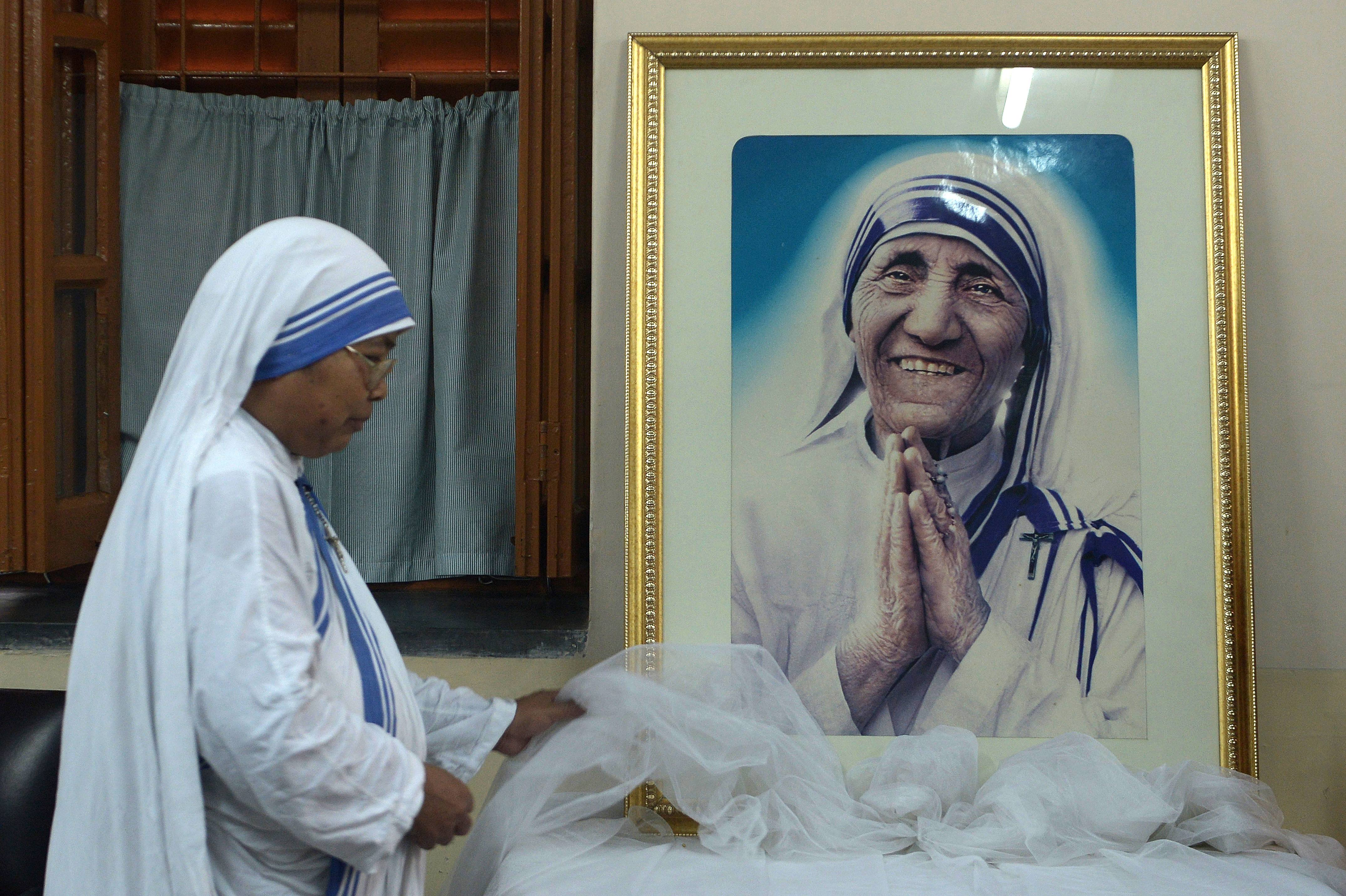 TOPSHOT - A nun of ?the Missionaries of Charity decorates a picture of Mother Teresa prior to a special prayer service at Mother House in Kolkata on December 18, 2015. Mother Teresa, set to become a saint after the Vatican announced recognition of her second miracle, became a global symbol of compassion for her care of the sick and destitute. AFP PHOTO/ DIBYANGSHU SARKAR / AFP / DIBYANGSHU SARKAR