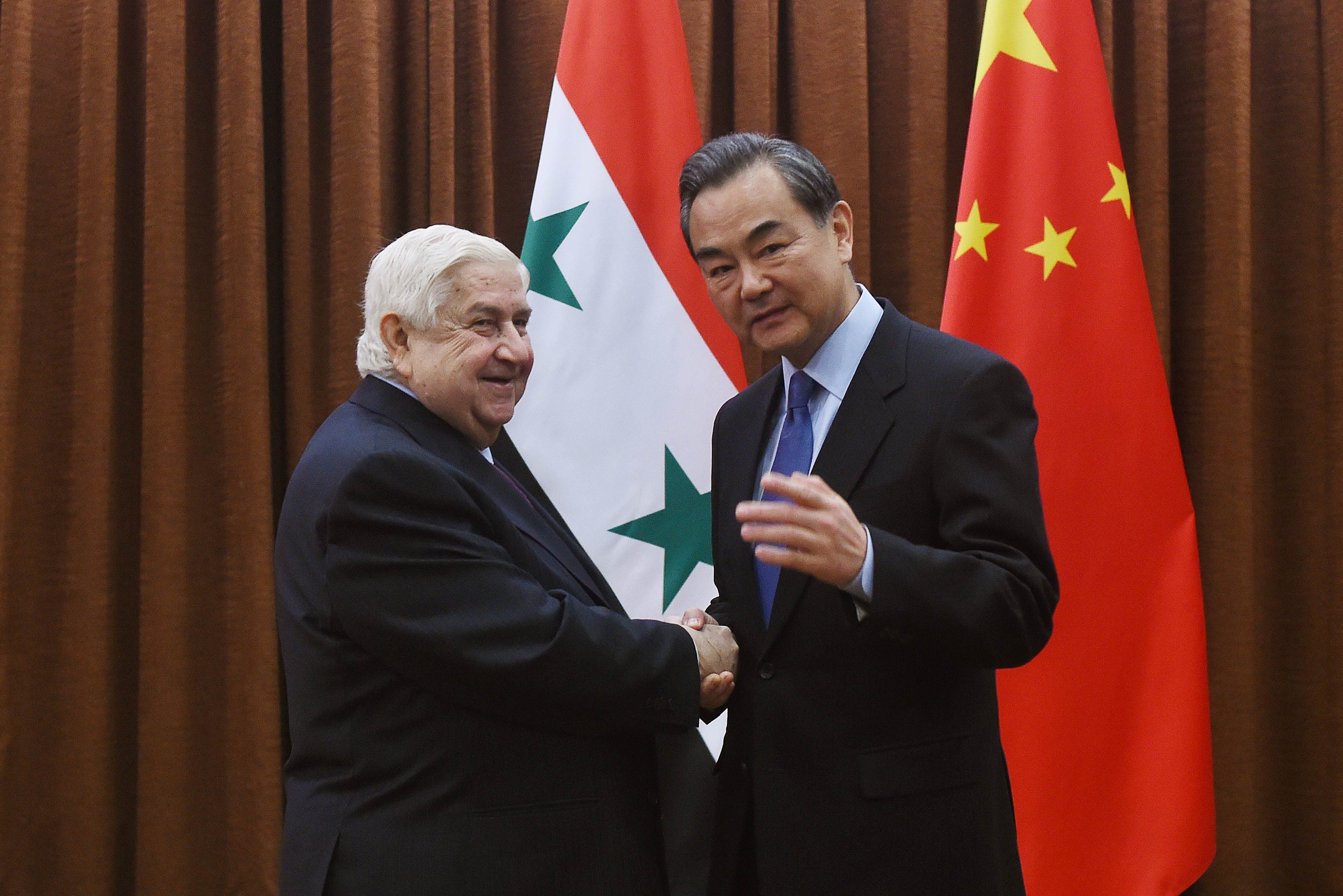 Syrian Foreign Minister Walid Muallem (L) is welcomed by Chinese Foreign Minister Wang Yi before a meeting in Beijing on December 24, 2015. Muallem is on a visit to China from December 23 to 26. AFP PHOTO / WANG ZHAO